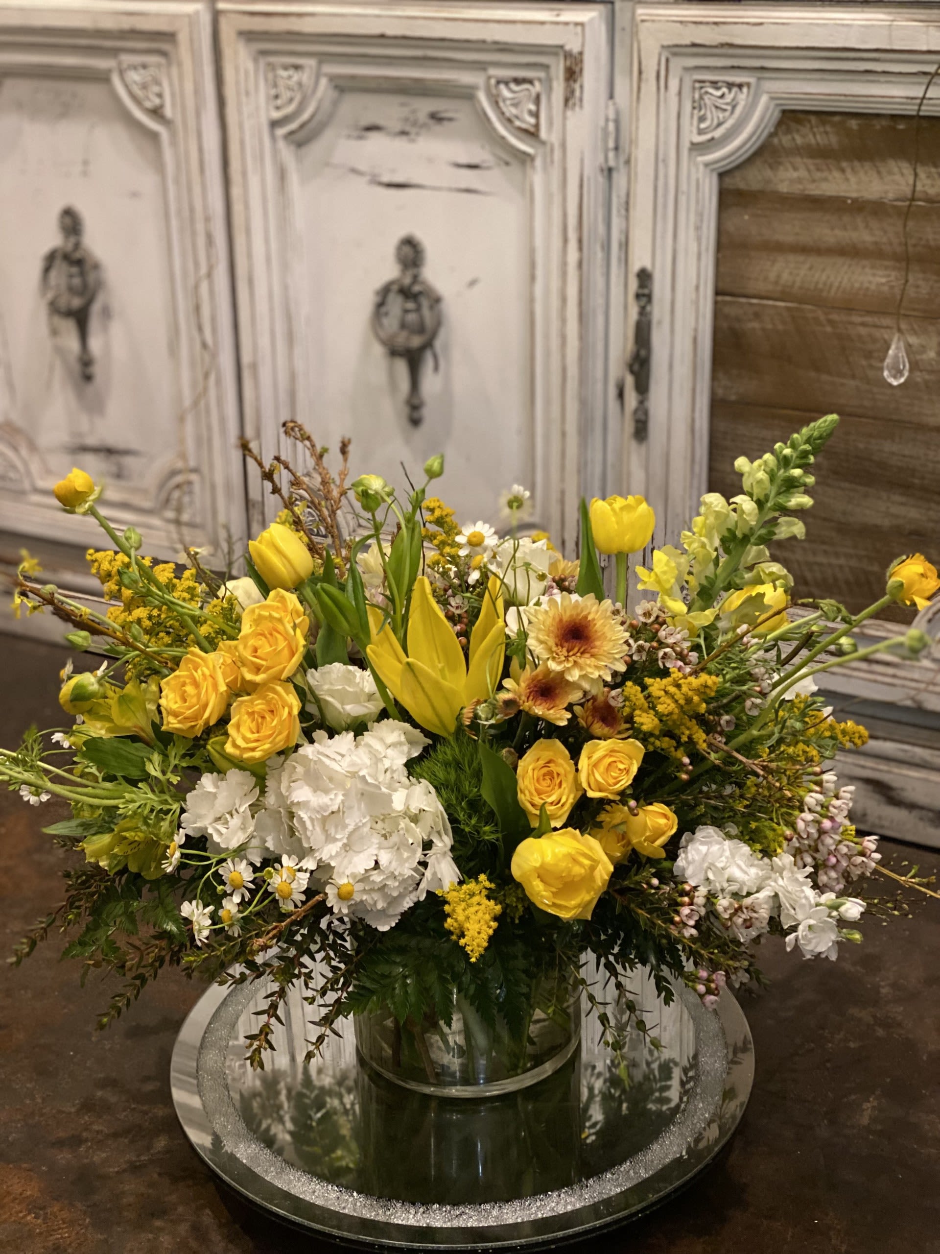 Yellow and white mixed flower arrangement in a clear glass vase