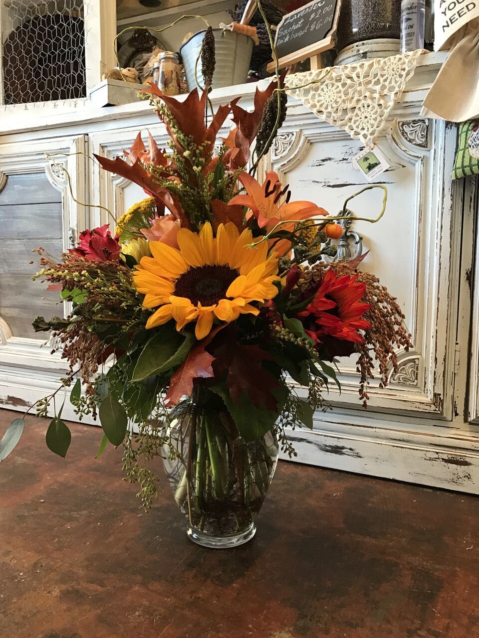 Autumn bouquet with a sunflower and orange lilies in a glass vase
