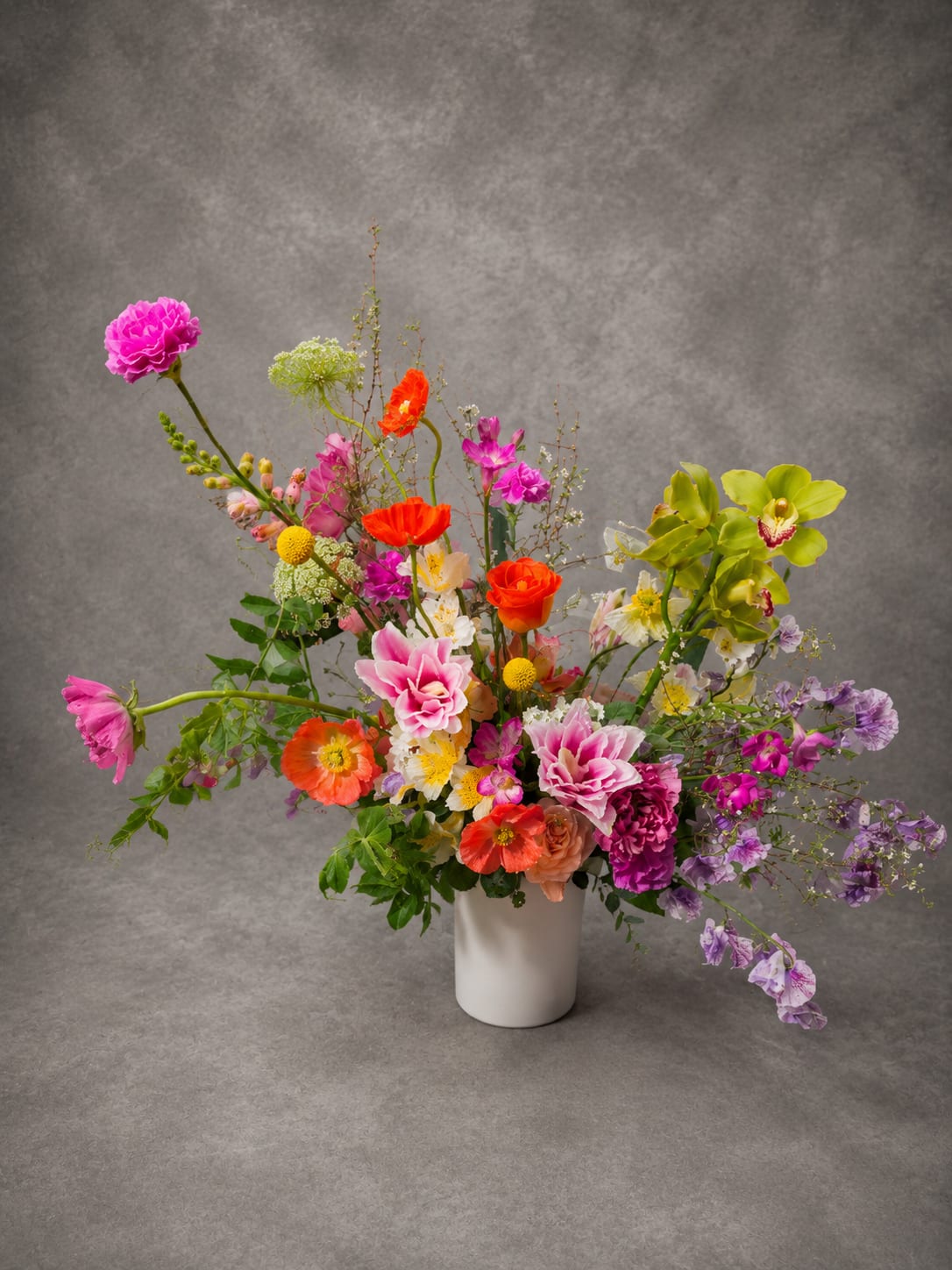 Wild Bloom - Bursting with movement, color, and seasonal beauty, Wild Bloom features an artistic blend of poppies, sweet peas, orchids, garden roses, and premium seasonal flowers. Designed in a loose garden style, this arrangement celebrates the natural beauty and spontaneity of flowers in bloom.