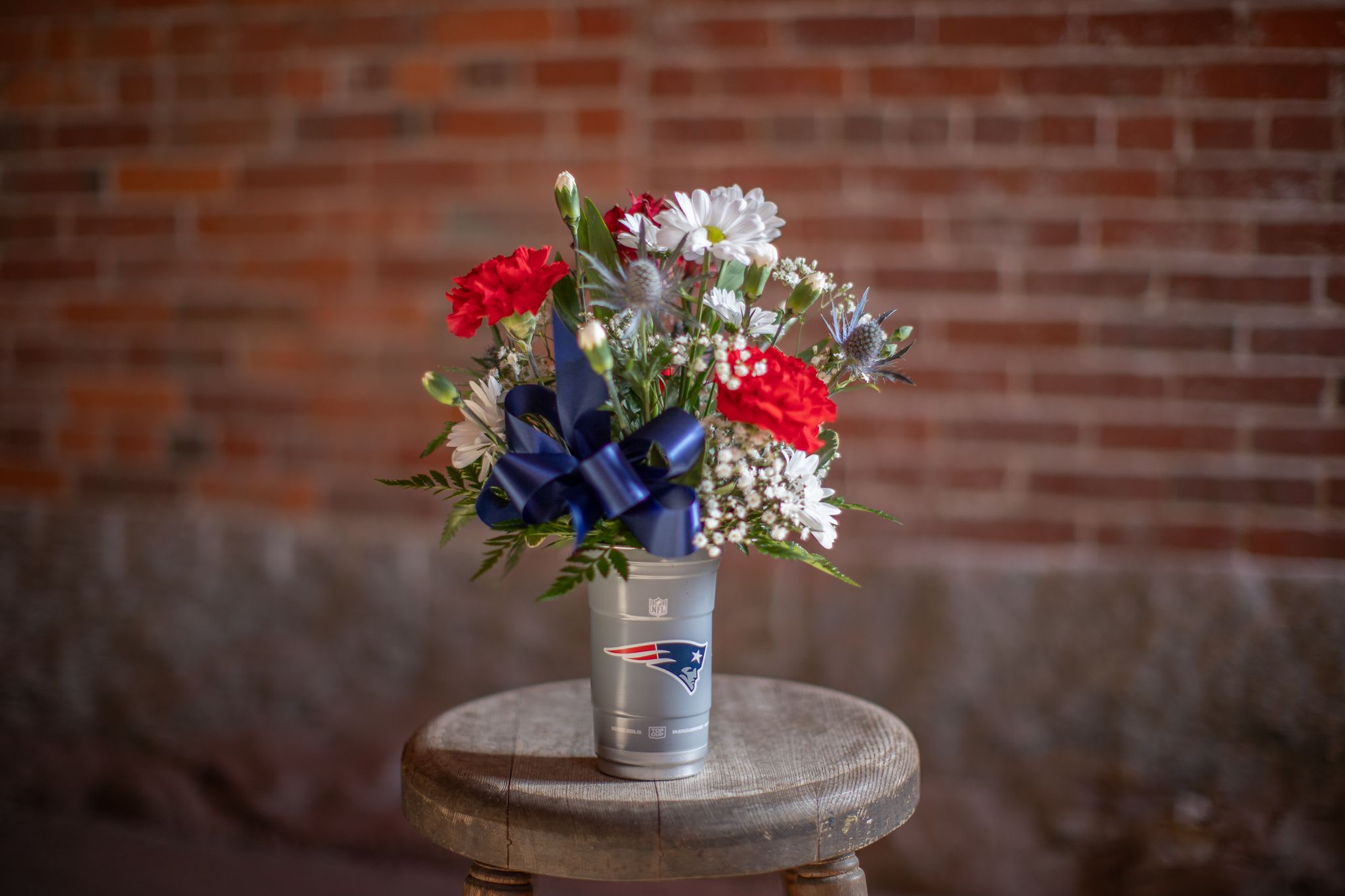Bouquet of red and white flowers in a silver cup with a blue ribbon