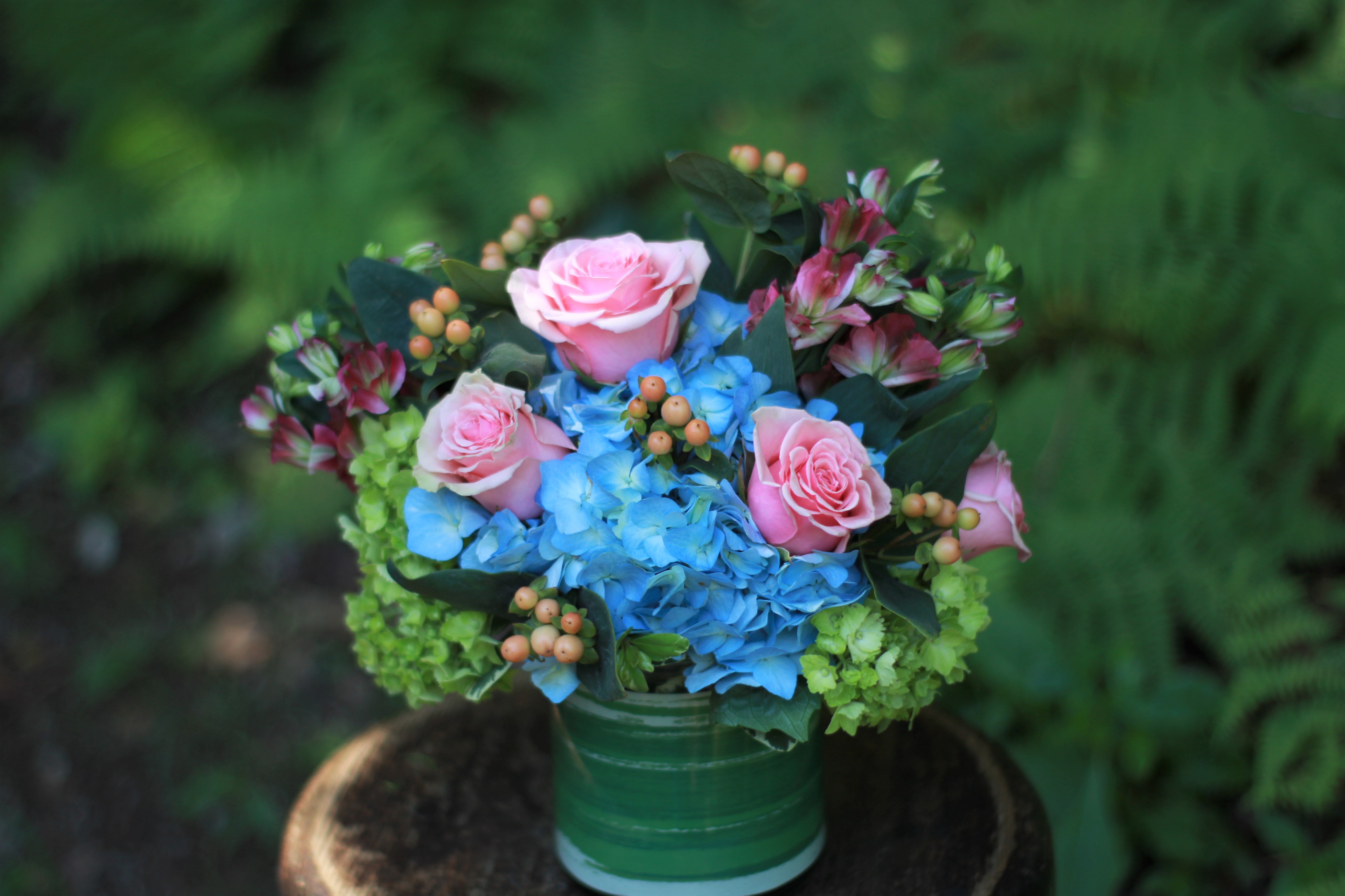 Pink roses and blue hydrangeas in a green vase