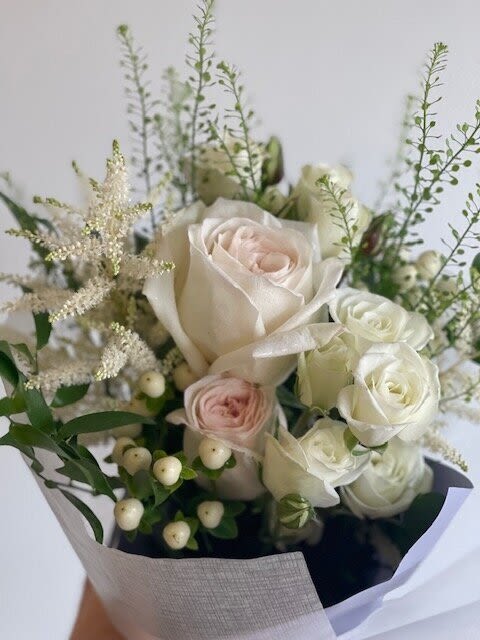 Bouquet of white and blush roses with airy filler and berries
