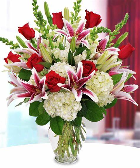 Bouquet of red roses, white hydrangeas, and pink lilies in a glass vase