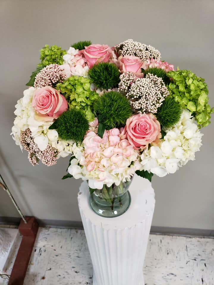 Pink roses and white hydrangeas arranged in a glass vase