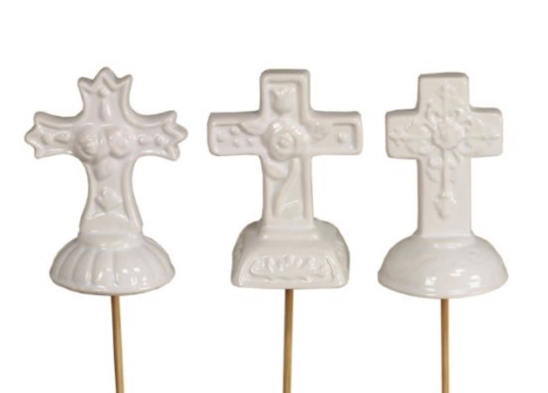 Set of three small white cross ornaments on picks with different embossed designs.