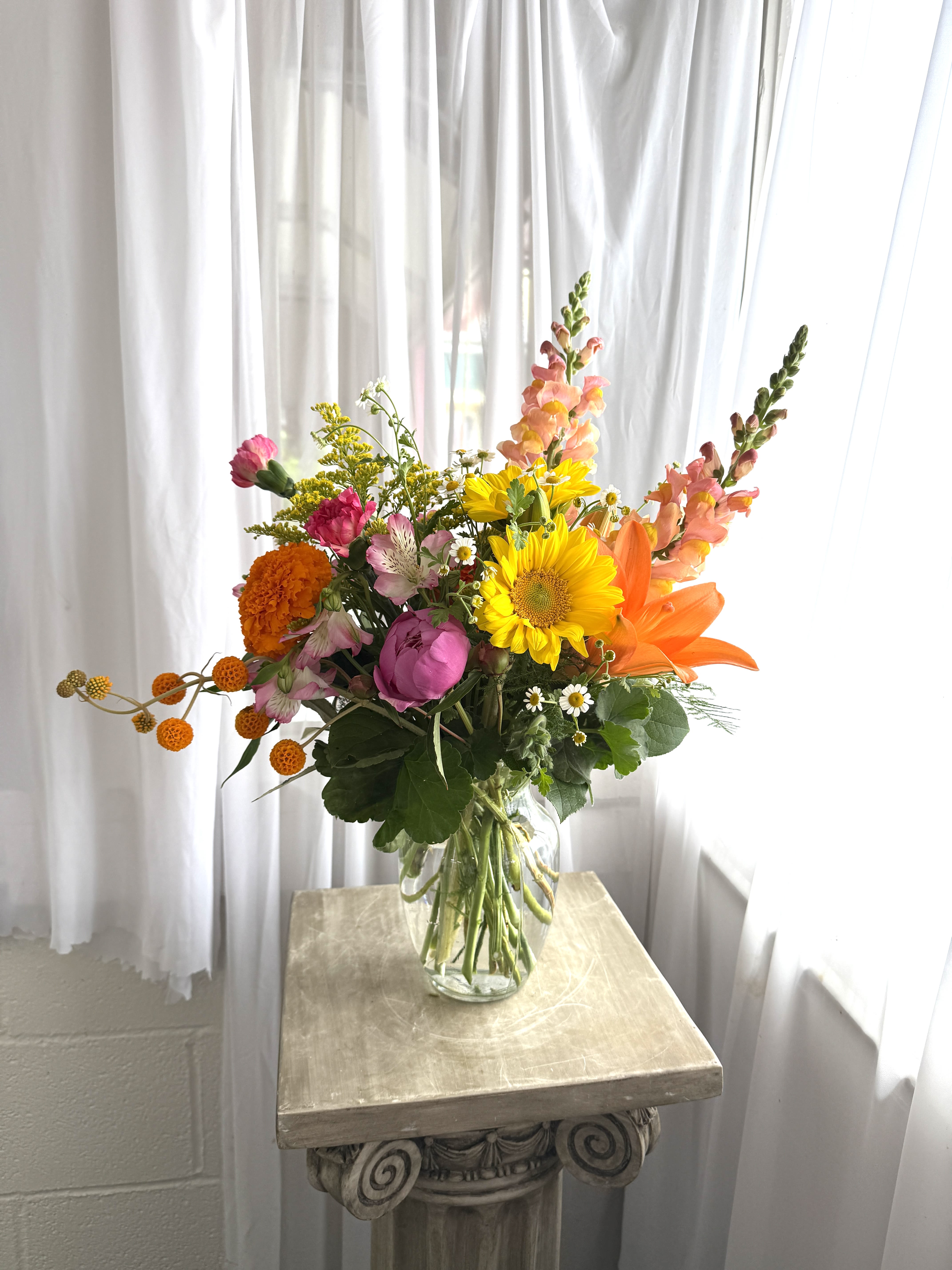 Valley Girls - Sunflowers, peonies, snapdragons, and more are gathered in a vibrant composition. We might have to substitute on what we have in stock, call shop to find out what we'll be using in yours.