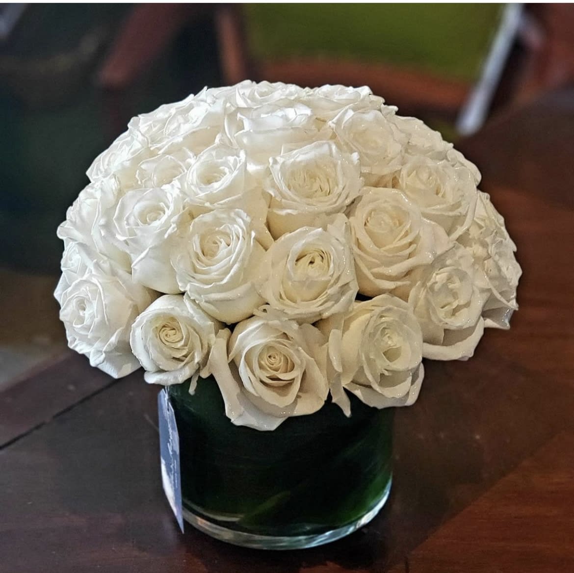 White rose bouquet in a dark green glass vase