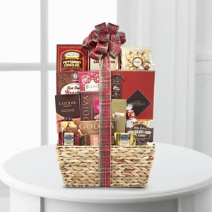 Woven gift basket filled with assorted gourmet snack boxes and tied with a plaid bow