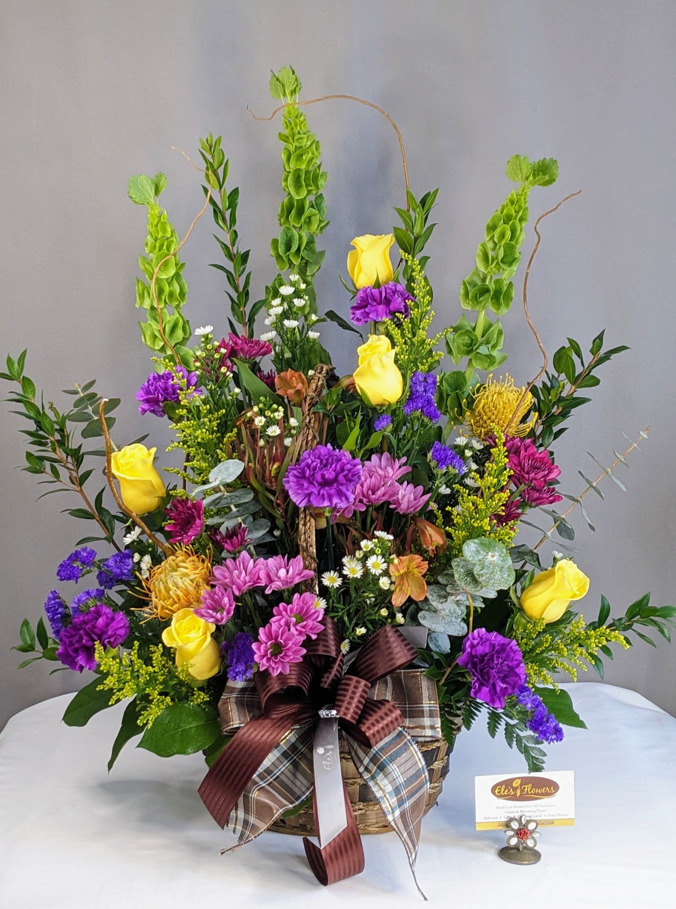Rustic Harvest Basket - Rustic Harvest basket brings together the darker tones of color, creating that rustic appearance. Shades of purples, oranges, yellows and greens are brought together in a wicker basket and fragrant greenery with natural embellishments. This is a great option for any memorial service.   The designs we create are custom and the blooms and containers will vary. We use the freshest product available to create the perfect floral combination for the recipient! If you have any special requests, please add those in the "special instructions" portion of your order to help us dial in your vision. Otherwise, our skilled designers, Brett &amp; Sara, will take it from here!  **Please note that the photos are examples only – floral selection may vary.**  Orientation: One - Sided Approximate Dimensions: 25"H x 20"W