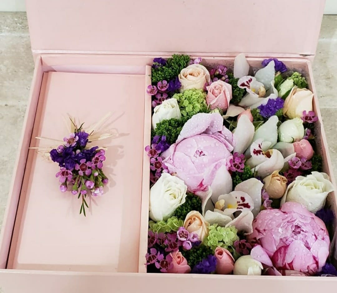 Pink gift box with a floral arrangement and matching boutonniere