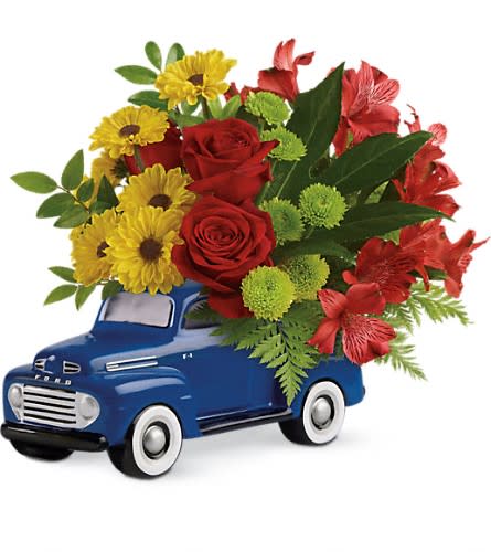 Red and yellow flower arrangement in a blue toy truck