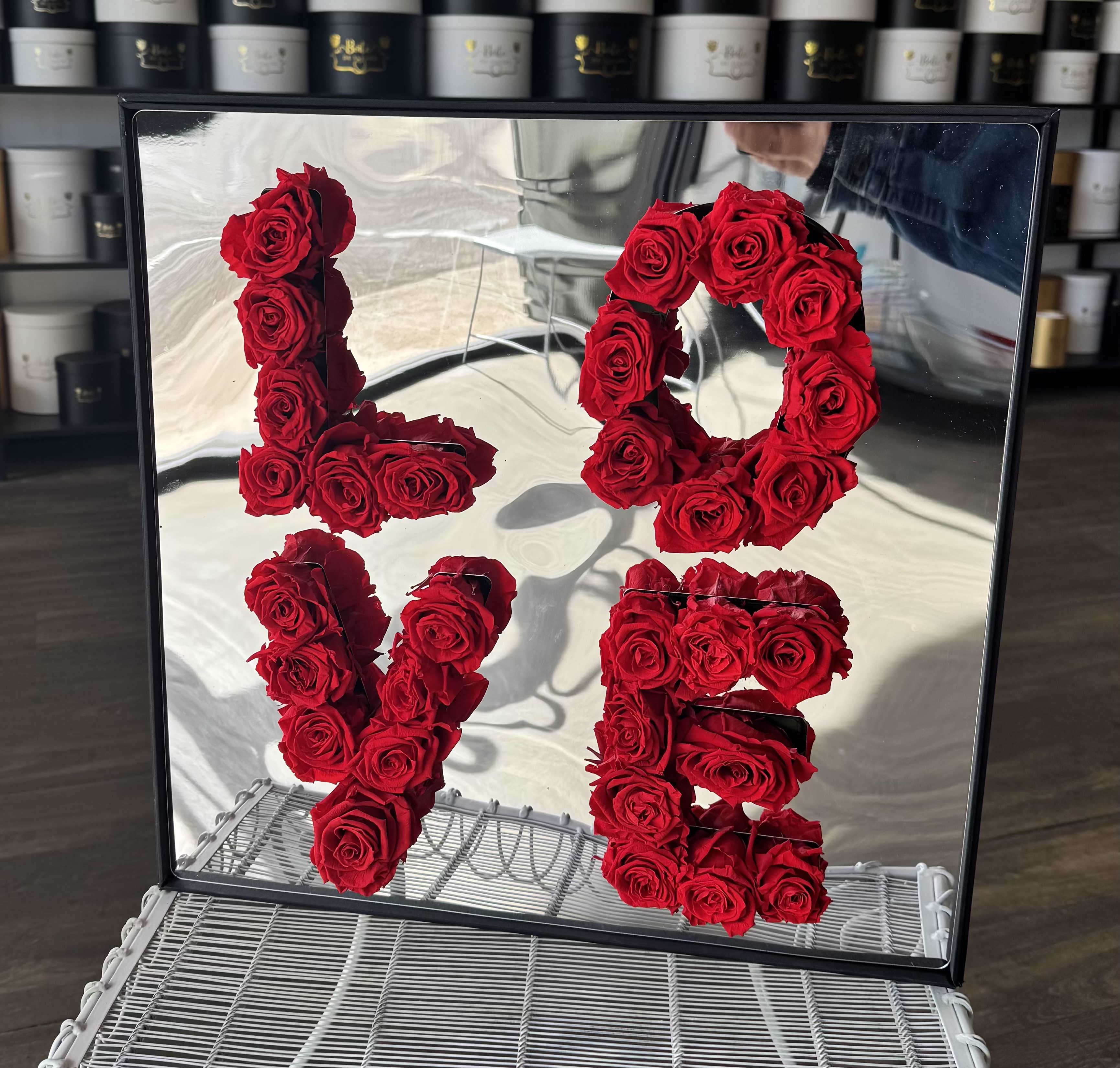 Red roses arranged as the numbers 1, 0, 1, and 5 in a mirrored frame