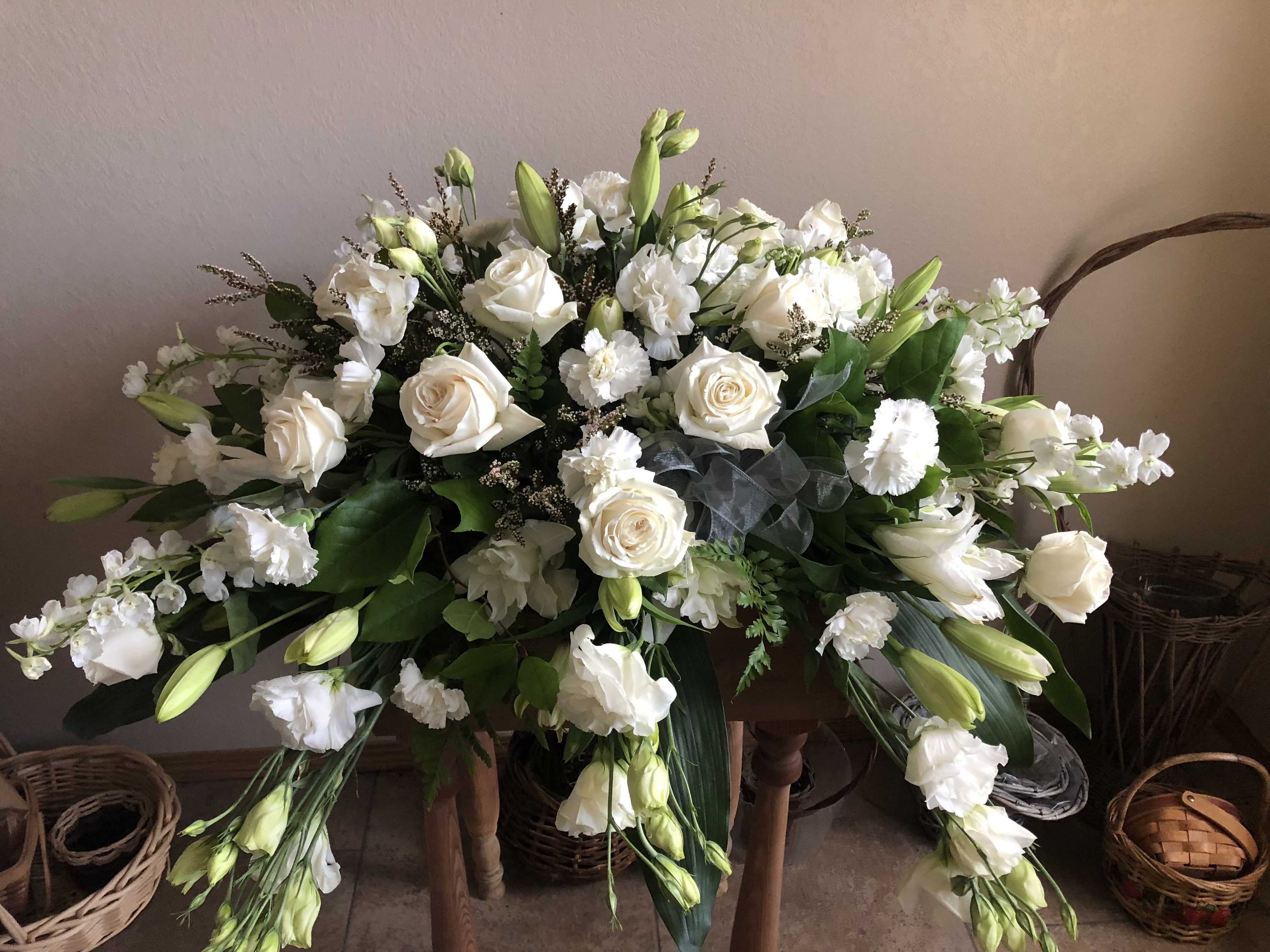 Large white floral arrangement with roses and lilies in a basket