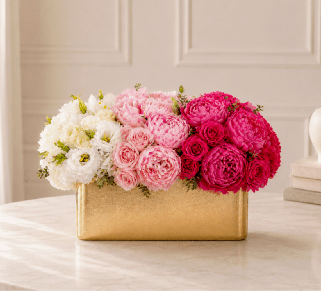 Pink and white flower arrangement in a gold rectangular box