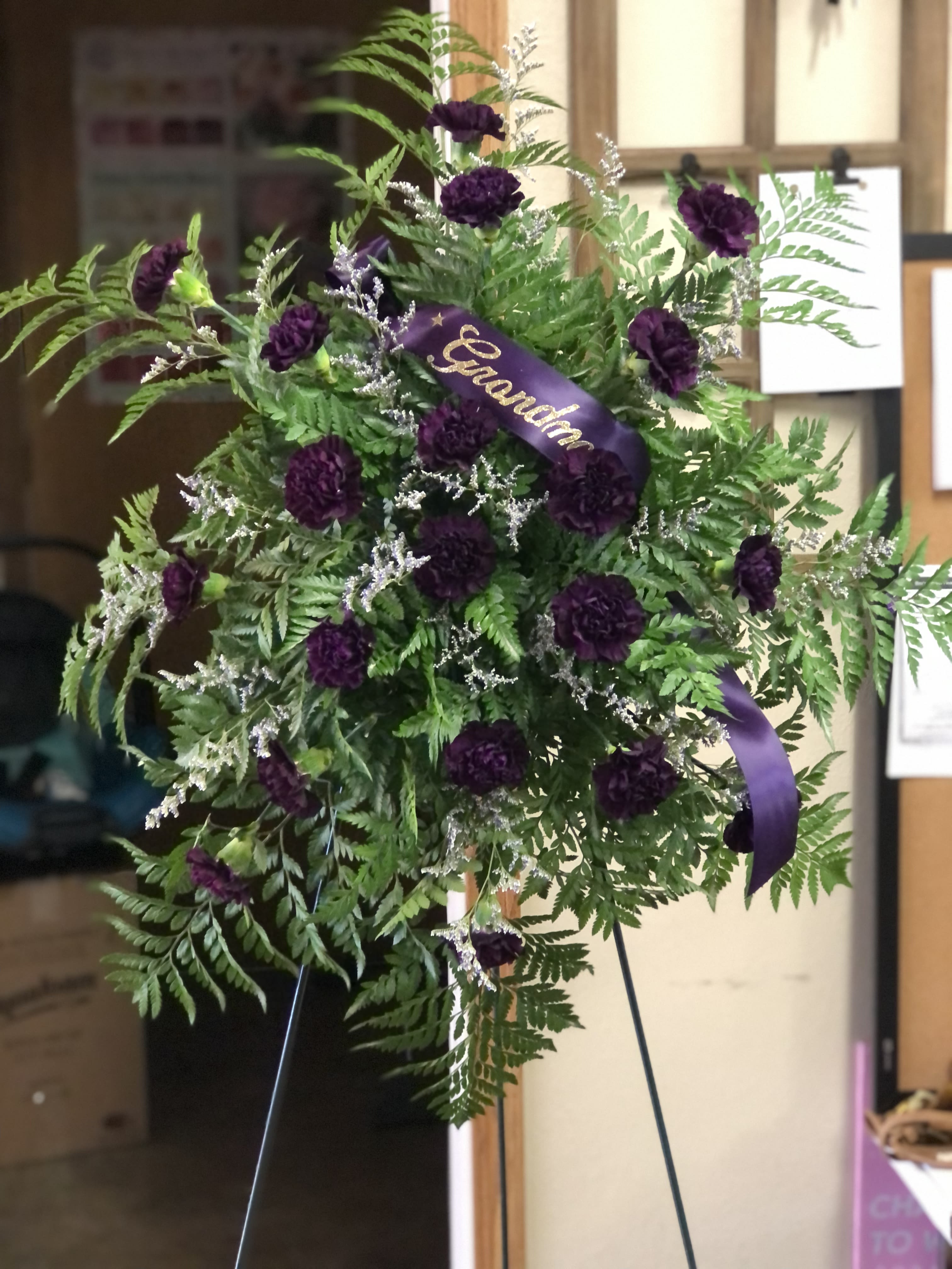 Standing floral spray with purple carnations and a purple ribbon
