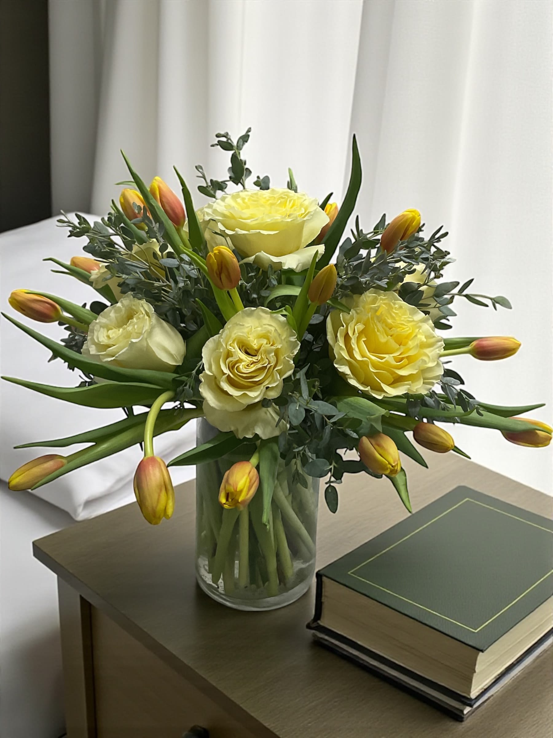 Blessed Sunrise - Blessed Sunrise features sunny yellow roses, soft tulips, and fresh eucalyptus arranged in a way that feels light, natural, and quietly uplifting. The warm yellow tones bring a sense of hope and comfort, while the soft textures keep the design relaxed and easy.  There’s a gentle, garden-style feel to this piece—nothing stiff or overworked—just fresh, clean beauty that settles into a space and brightens it without trying too hard.  A thoughtful choice for birthdays, thank-you gifts, sympathy, thinking of you, get well, or simply sending something to lift someone’s day.  Each arrangement is designed with the freshest seasonal stems available. Colors and varieties may vary slightly to ensure the best overall look.  Available for local flower delivery through Aspen Tower Florist, serving Greensburg and Shelbyville along with Rushville, Batesville, Westport, Oldenburg, St. Paul, Waldron, and Milroy.