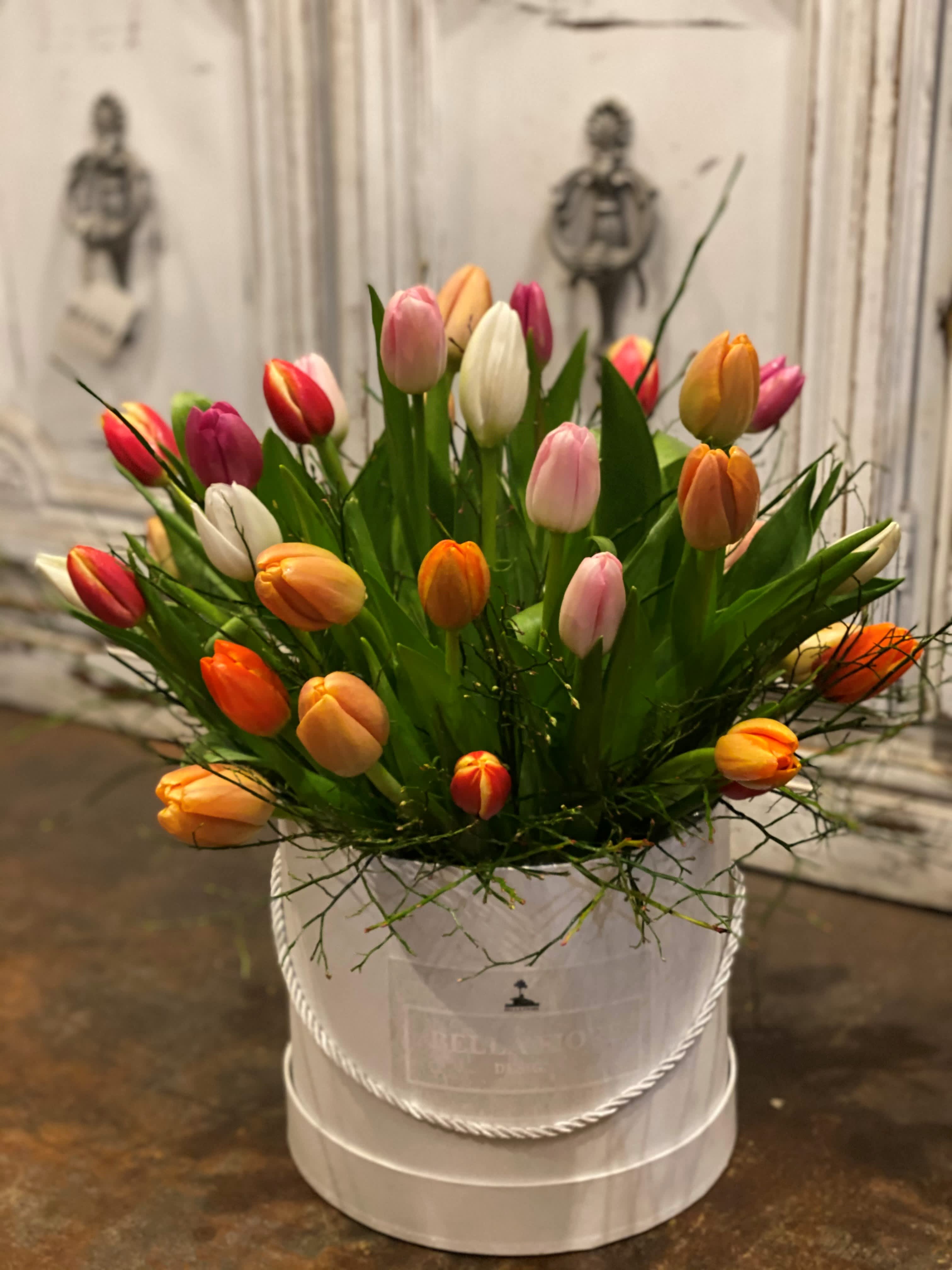 Tulip Paradise  - A spring colored assortment of tulips come together to form the perfect bouquet arranged beautifully in ah hatbox, colors and varieties may vary due to local availability. 