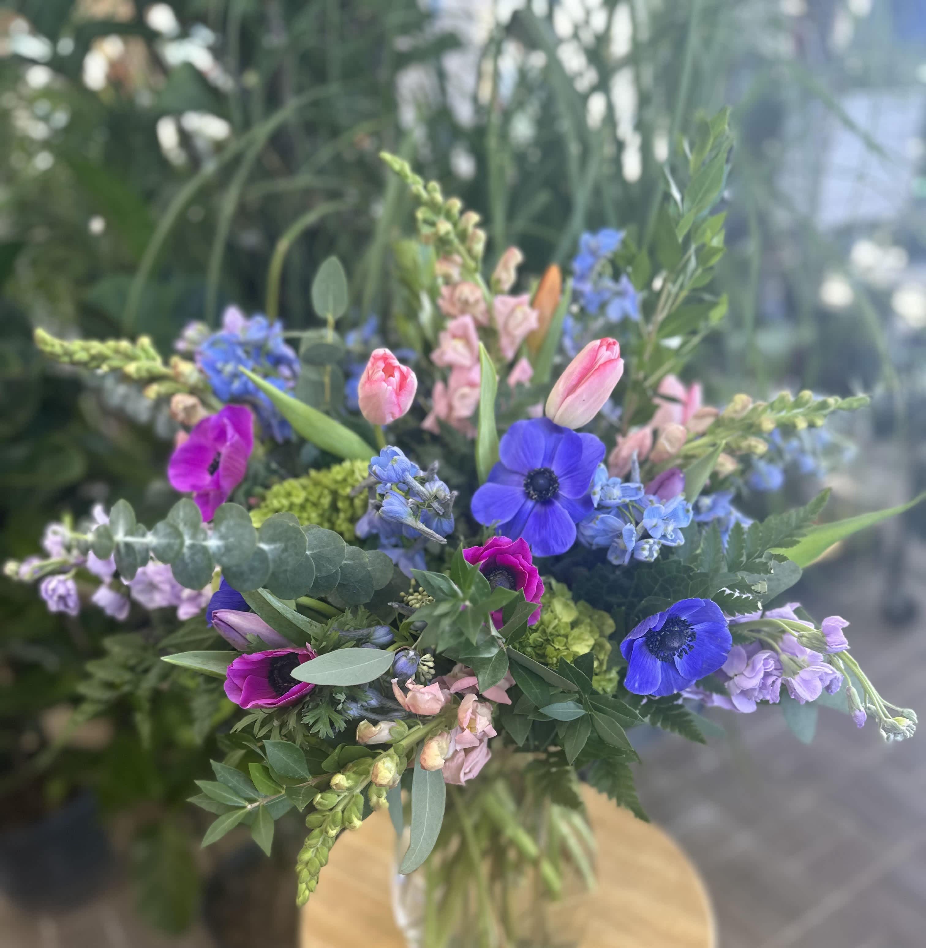 Mixed bouquet with blue and pink flowers in a clear vase