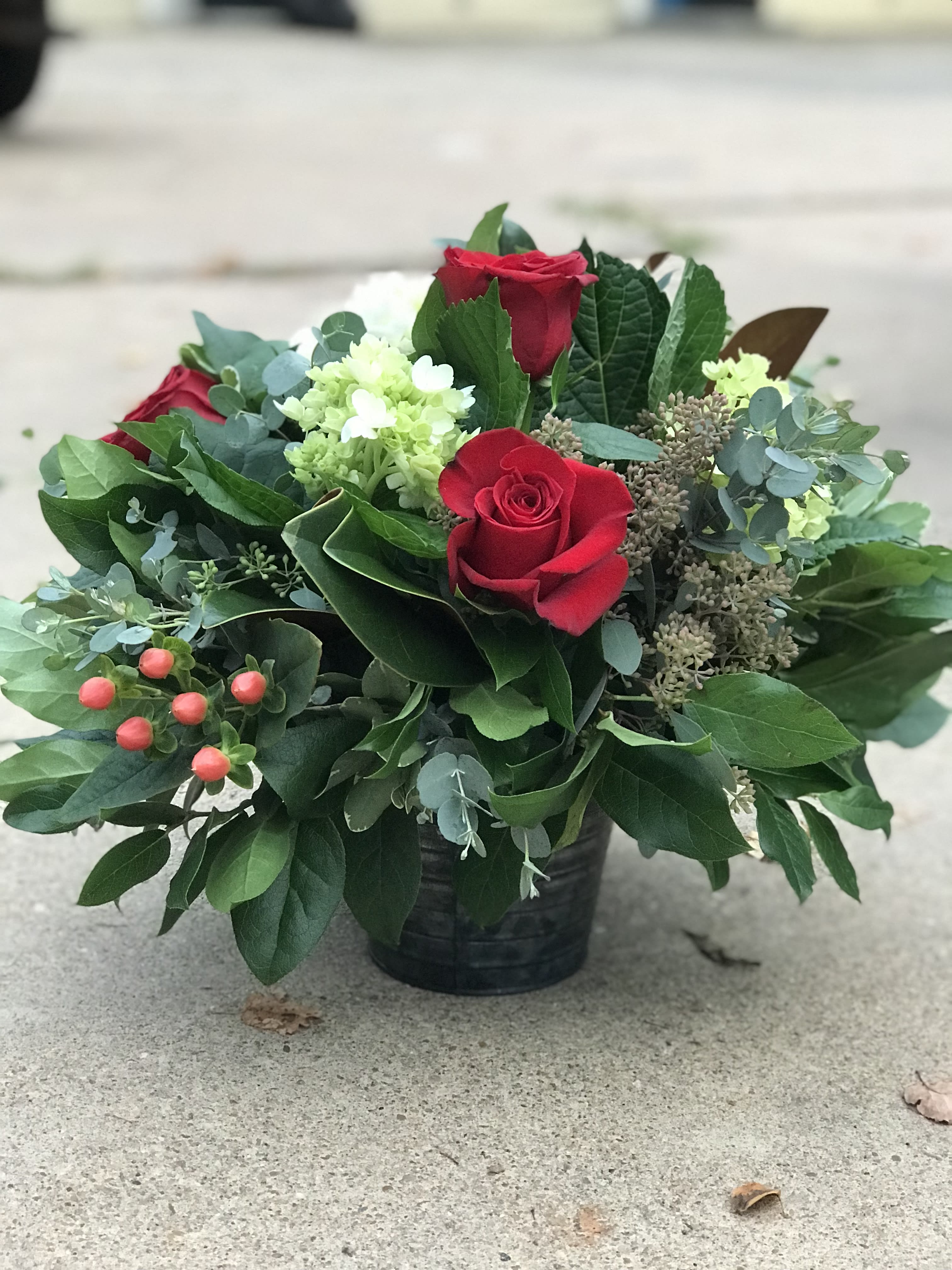 Red roses and pale green blooms in a black container
