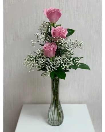 Pink roses arranged in a tall glass vase with white filler flowers