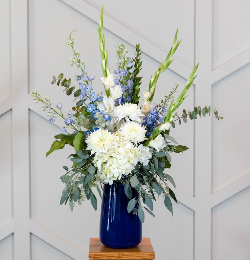 White and blue floral arrangement in a cobalt vase