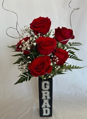 Red roses arranged in a tall black vase with a GRAD sign