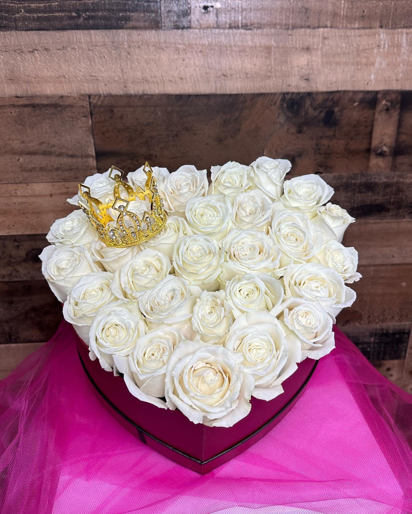 Heart-shaped box of white roses with a gold crown topper