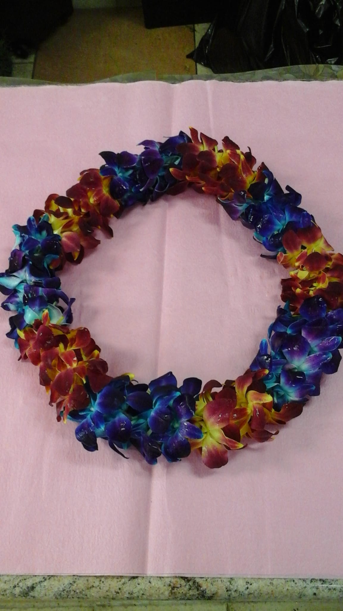Colorful flower lei made of clustered blossoms on pink paper