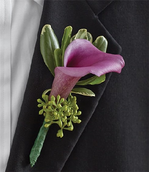 Purple calla lily boutonniere with green accents on a black lapel