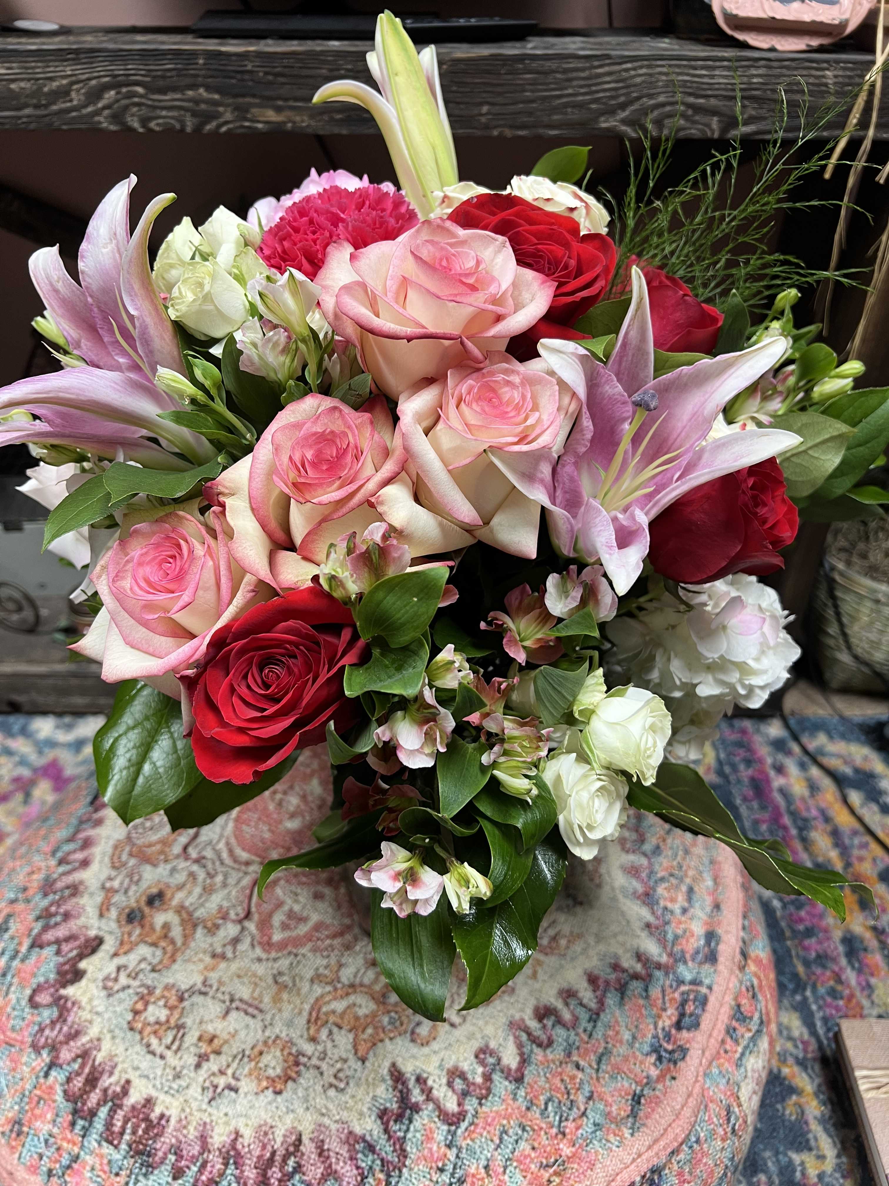 Bouquet of pink and red roses with lilies and white filler flowers