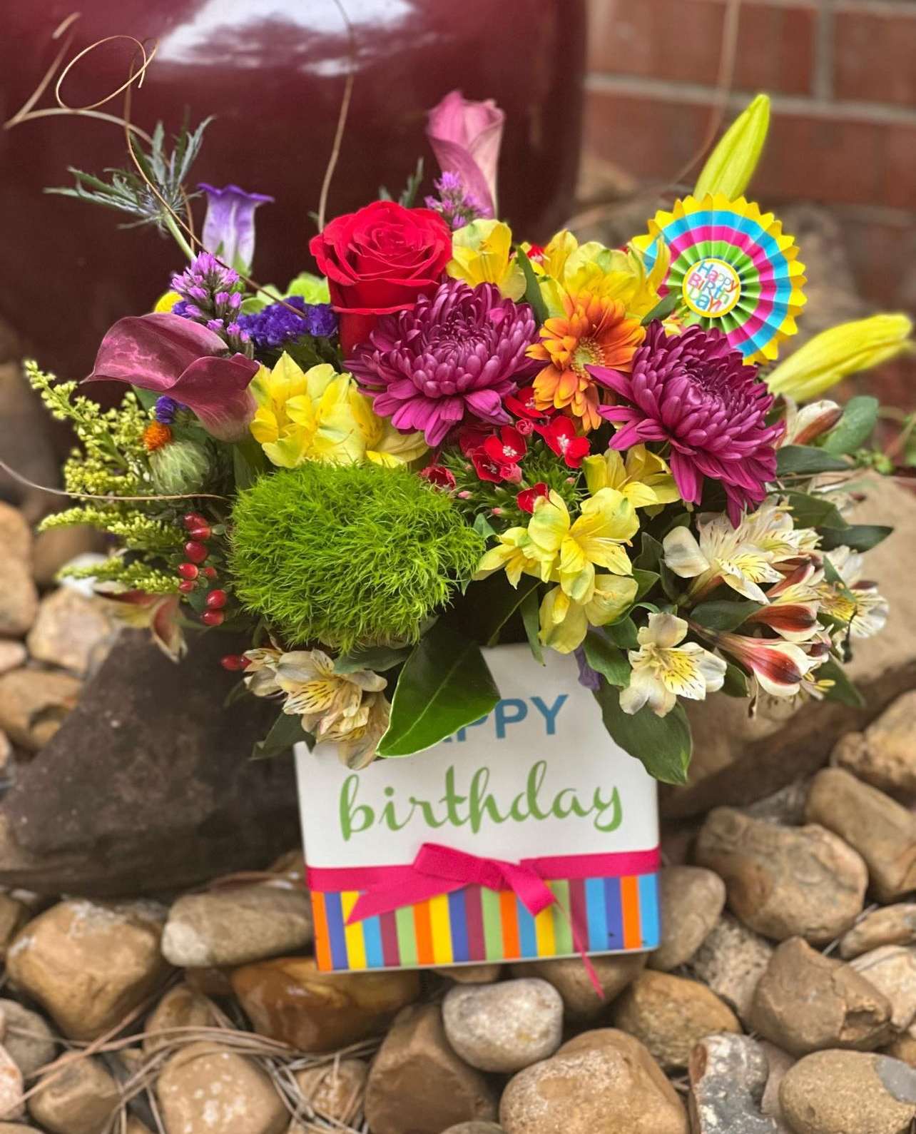 Colorful birthday flower arrangement in a gift bag with a ribbon