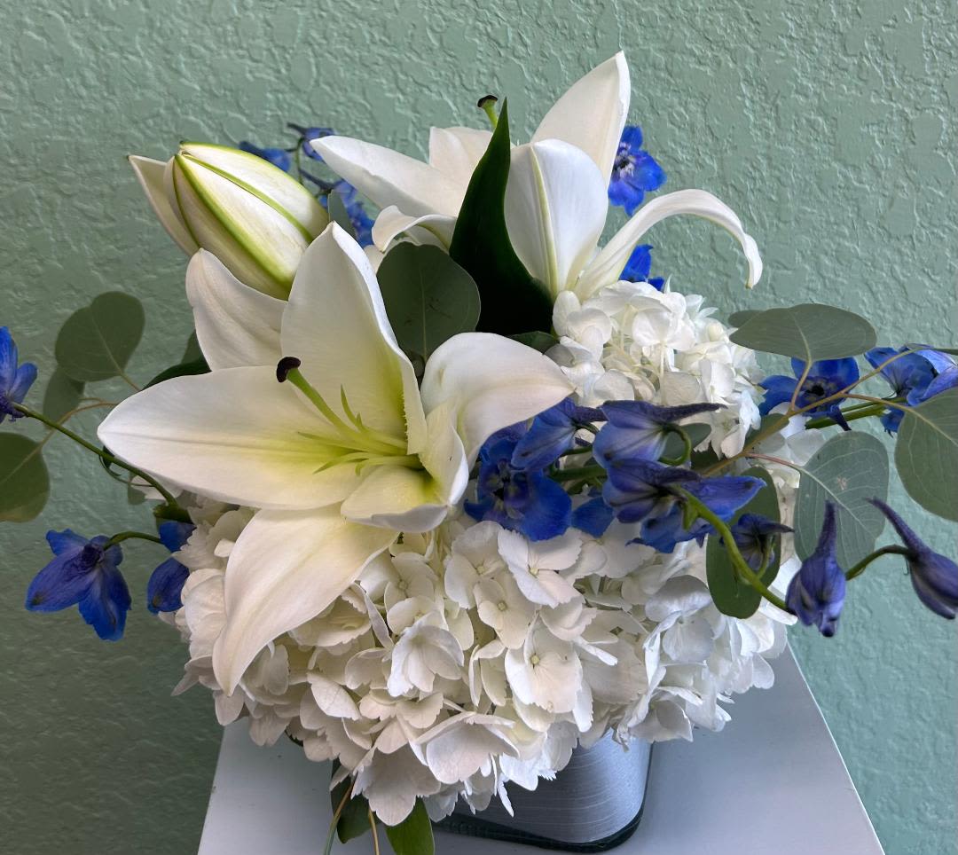 CFE109 - A modern compact arrangement of high end blue and white flowers such as hydrangeas, lilies and other blooms. 