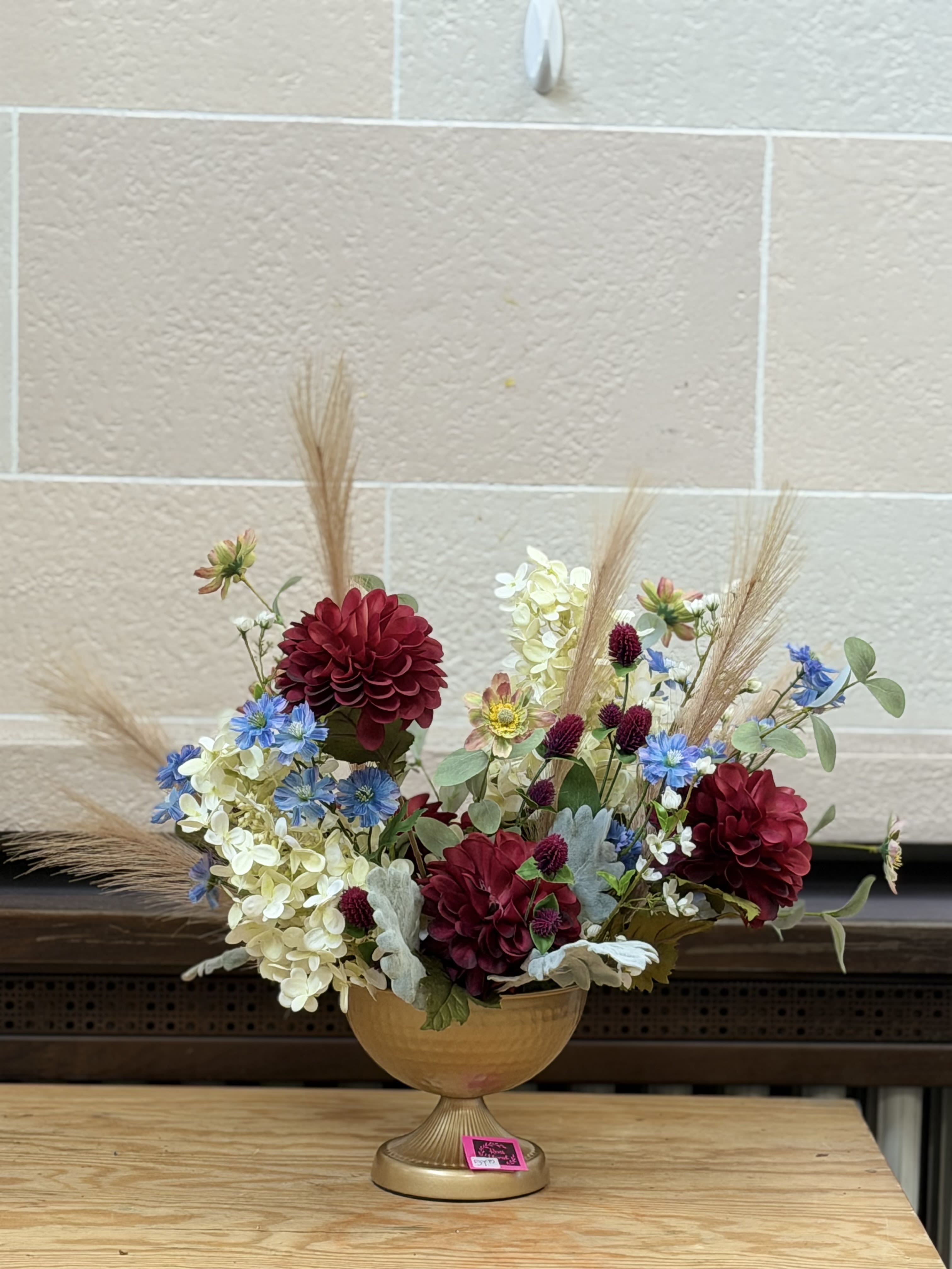 Modern Artificial Centerpiece  - A gold container filled with artificial blooms in a modern shape. 