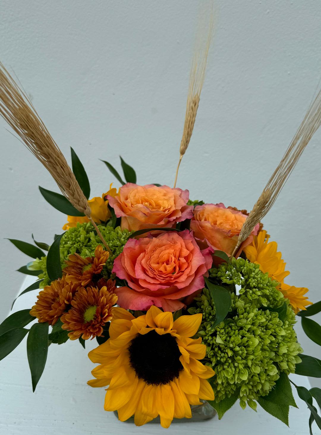 CFE111 - A low compact arrangment of sunflowers, green hydrangea and roses in fall tones. 