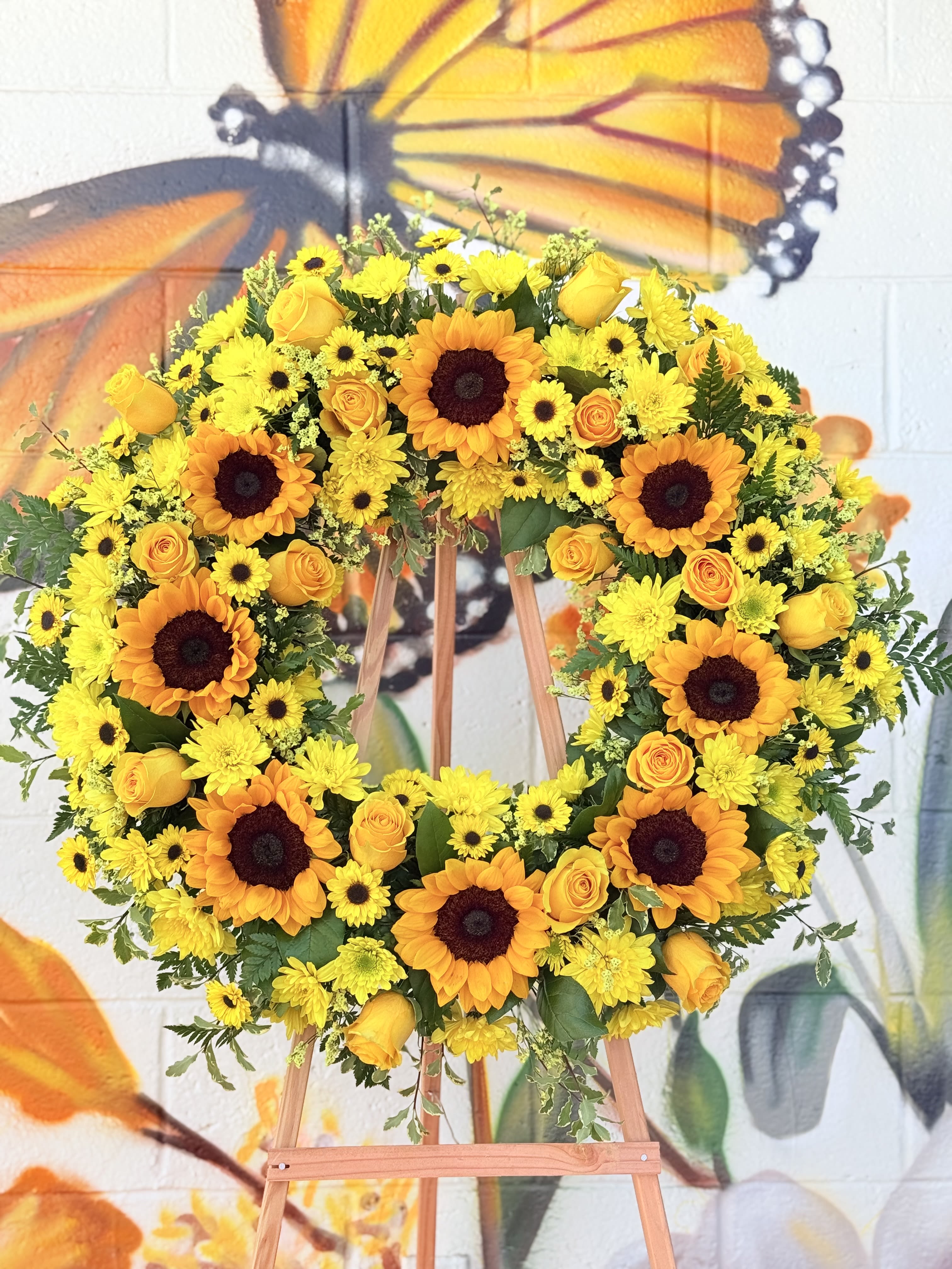 Ray Of Sunshine  - A radiant sympathy wreath featuring sunflowers , yellow roses, and cheerful yellow blooms to honor a loved one with warmth,love, and  remembrance.
