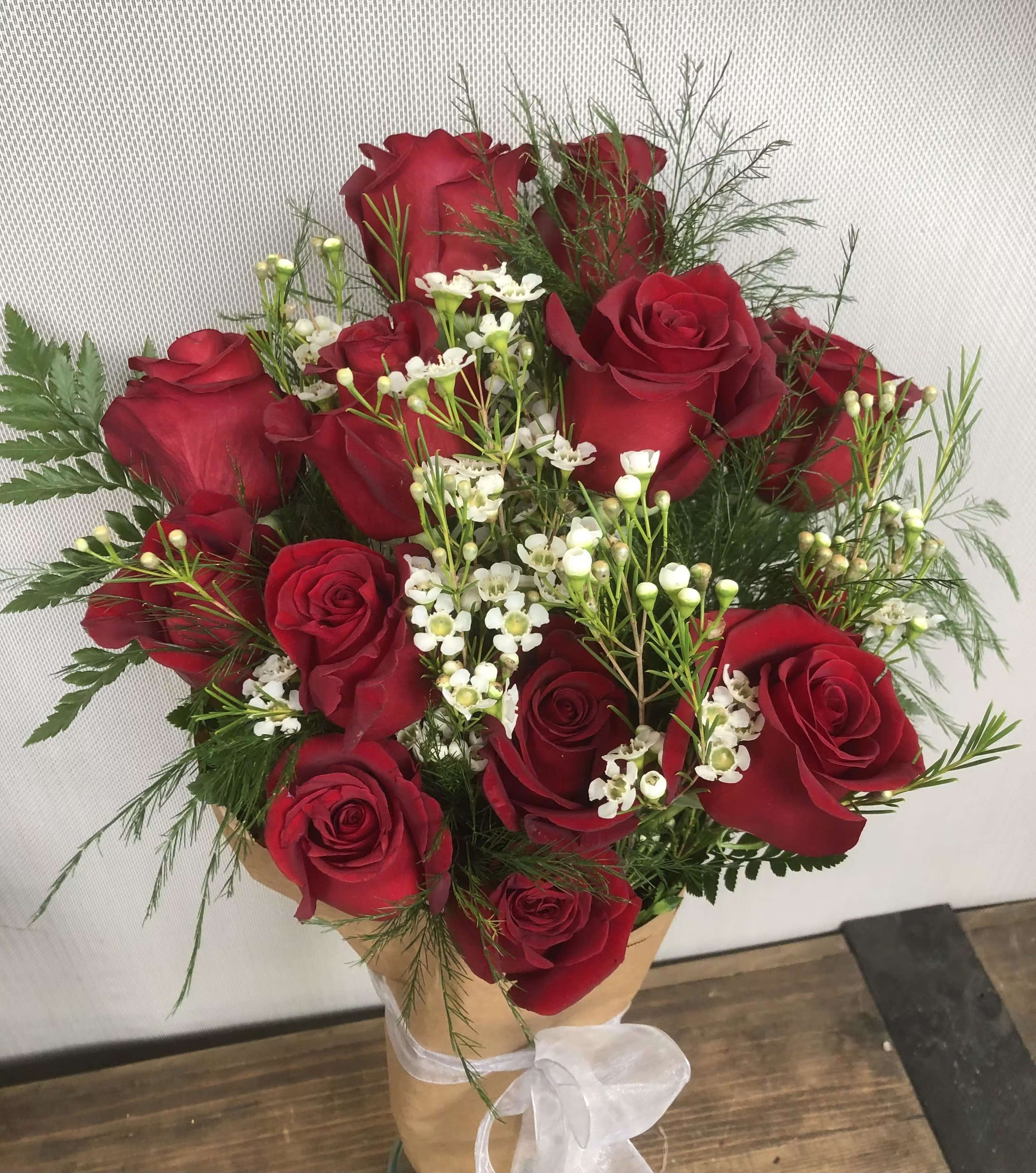 Bouquet of red roses with white filler flowers in brown paper wrap