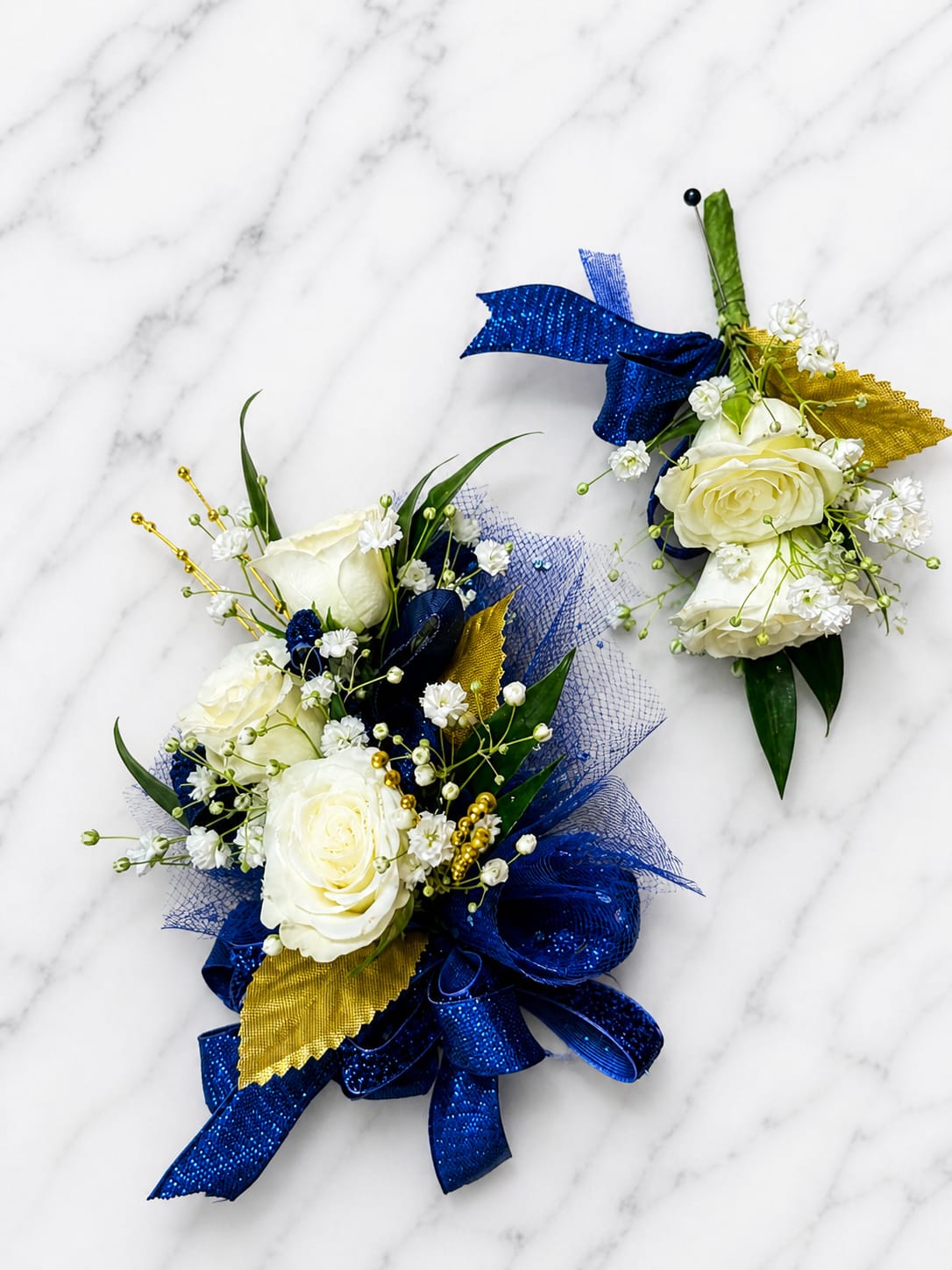 Sapphire Dreams Formal Set - Because each corsage and boutonniere is individually designed, no two sets will be exactly alike. Ribbon, filler flowers, bracelets, decorative accents, and other design elements may vary based on availability. While individual details may differ, the overall color palette, roses or flowers, style, and appearance of the Sapphire Dreams collection will be maintained.