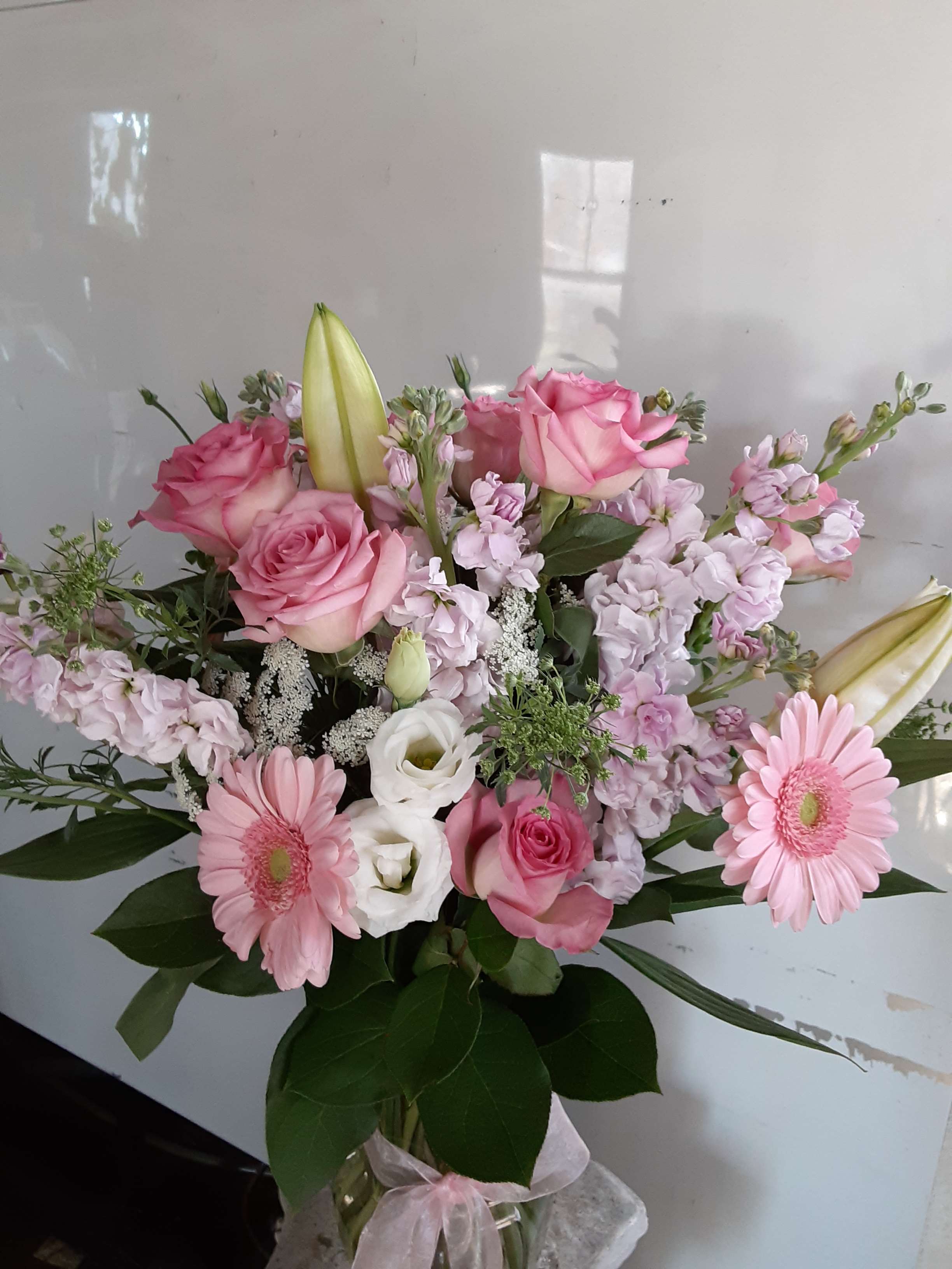 Pink and white mixed bouquet with roses, lilies, and daisies in a glass vase