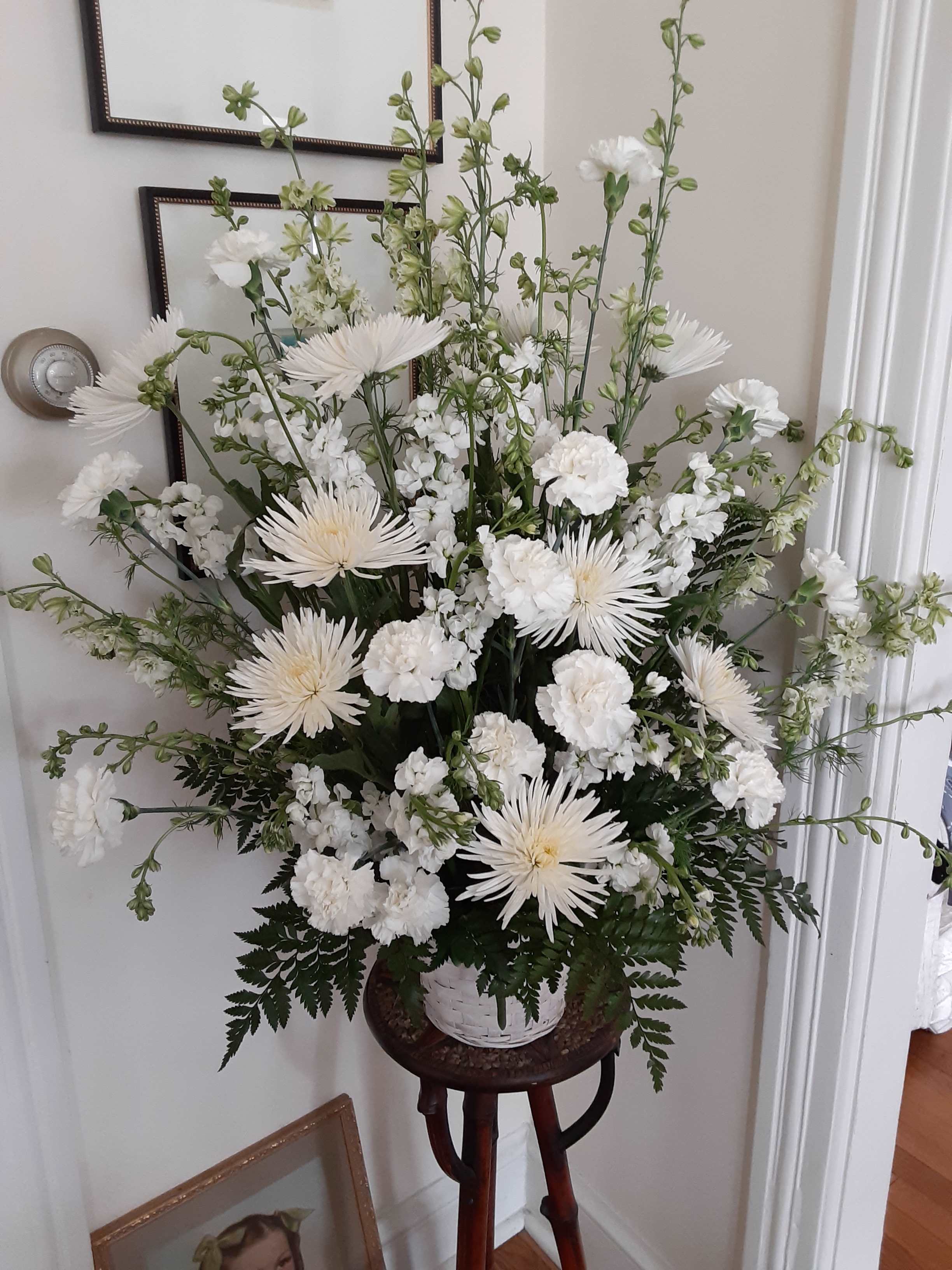Tall white floral arrangement in a basket on a stand