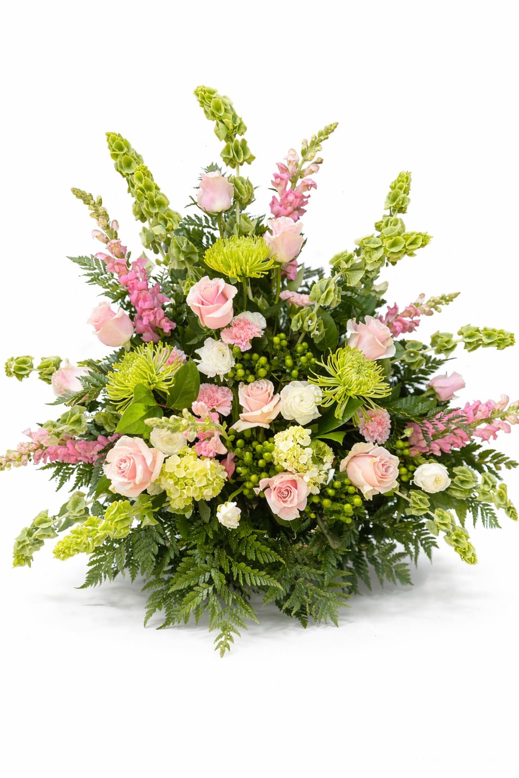 Blushing Garden Tribute - Soft pink roses and airy hydrangea tones give this large sympathy arrangement a gentle, comforting presence - a flower arrangement perfect for a cheerful sympathy tribute, spring celebration, anniversary, or birthday. The Blushing Garden Tribute's wide, layered shape and soft chartreuse accents create a fresh, romantic look that helps the person you're honoring feel seen and remembered.  This full design features pink roses, white blooms, lime-green chrysanthemums, soft carnations, and tall green-and-pink snapdragon spikes arranged with abundant fern-like foliage and clustered green accents at the center. The composition spreads outward in a generous display, blending textures from velvety rose petals to feathery foliage and the vertical interest of snapdragons for a refined, uplifting silhouette.  Ideal for sending comfort or celebrating a life, this arrangement reads as both formal and tender - the kind of tribute that brings warmth and calm to a room. Available in a large, full size as shown; please contact us for delivery timing or personalization requests to ensure it arrives fresh and ready to comfort.