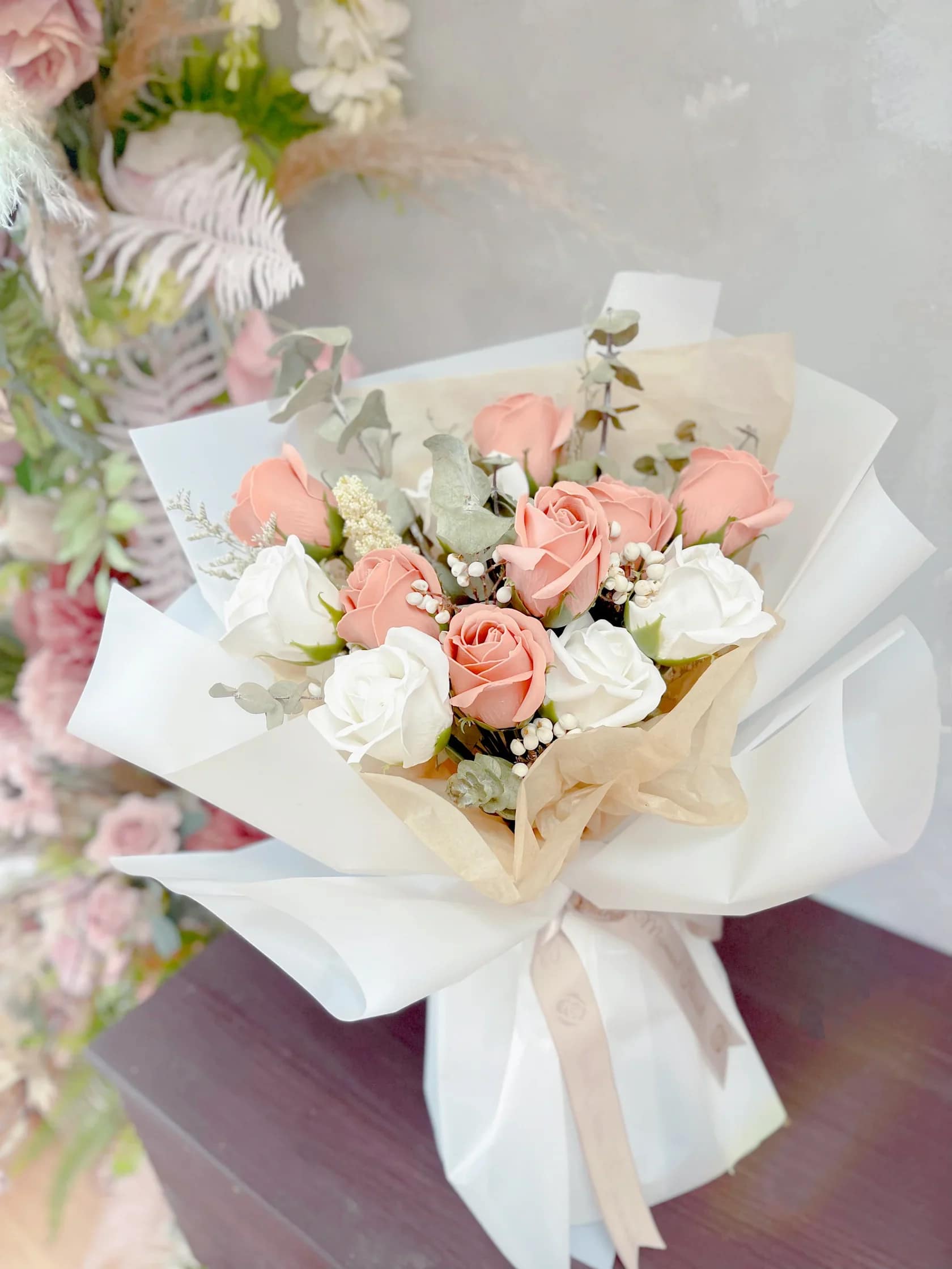Bouquet of blush and white roses wrapped in white paper