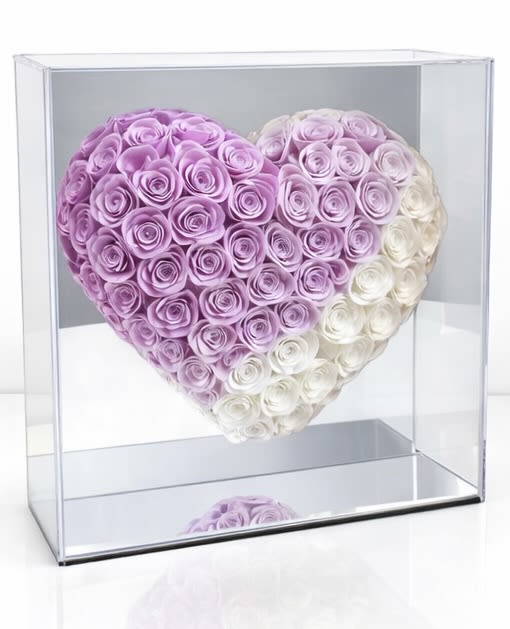 Heart-shaped arrangement of pink and white roses in a clear display box