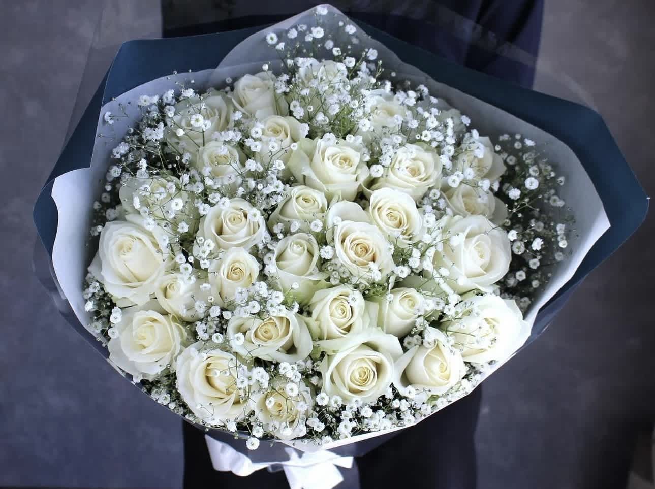 Bouquet of white roses and baby's breath wrapped in dark paper