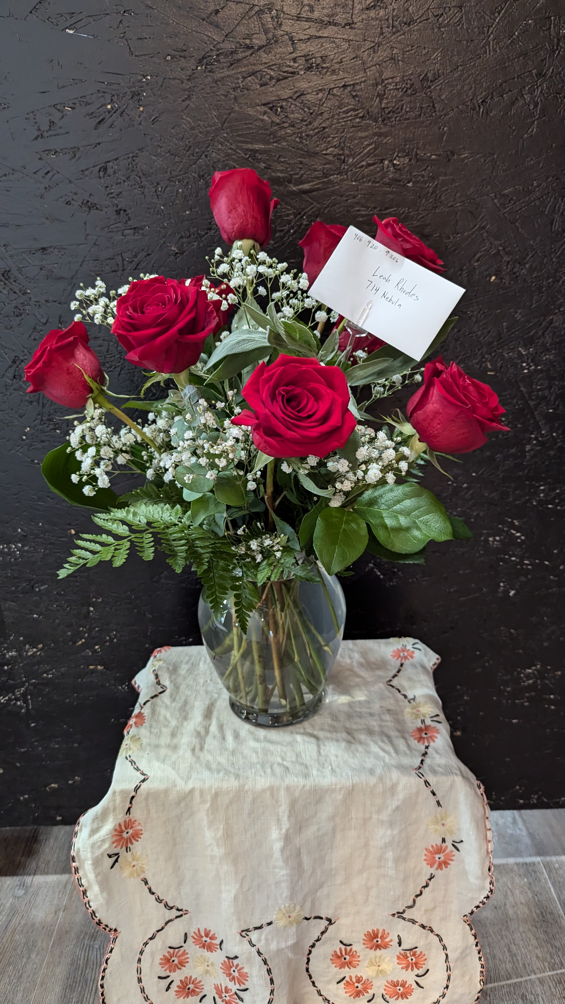 Red Roses - Deep, velvety red roses clustered with airy white baby's breath create a timeless bouquet that says "I'm thinking of you"-perfect as a birthday bouquet, anniversary roses choice, or a simple everyday gift of love. The arrangement reads romantic and classic, designed to make the person you're sending it to feel cherished and noticed without being overdone.  Several long-stem red roses sit in a clear glass vase with mixed greenery for contrast; some blooms are fully open while others remain in bud for a natural, hand-tied look. A card holder and note card are included so you can add a personal message. Vase-ready and easy to display, this compact arrangement brings rich color and gentle texture to a bedside table, desk, or mantel-no fuss care: fresh water and a cool spot will keep the roses looking their best.
