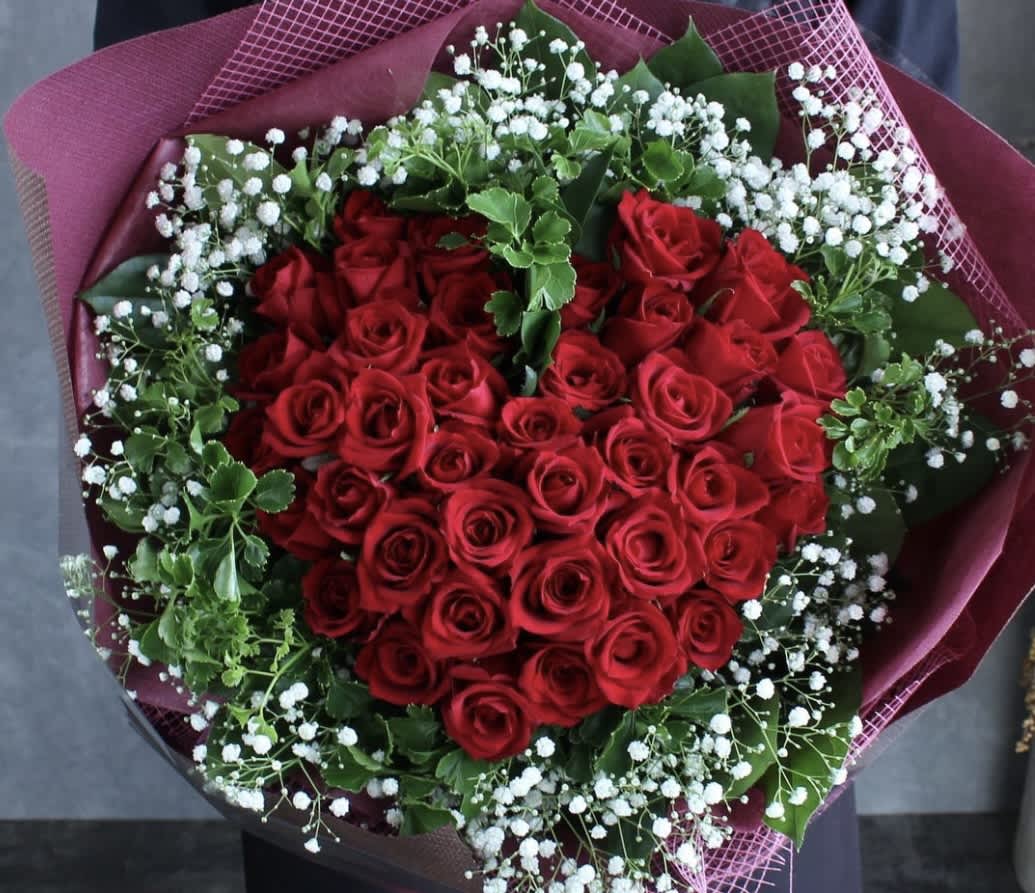 Heart-shaped bouquet of red roses with white baby's breath