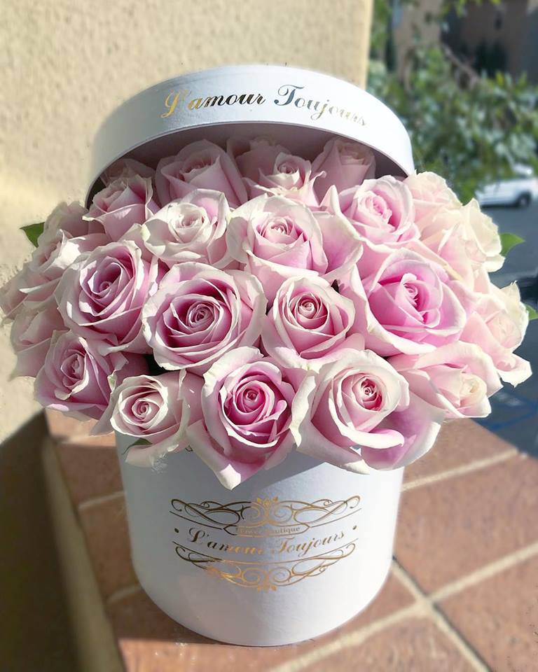 Round white hat box filled with tightly packed light pink roses