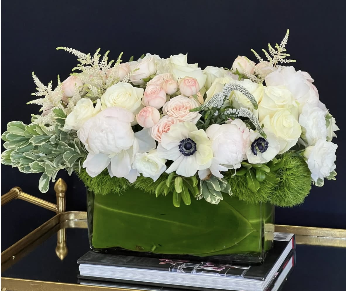 White and blush floral arrangement in a green glass vase
