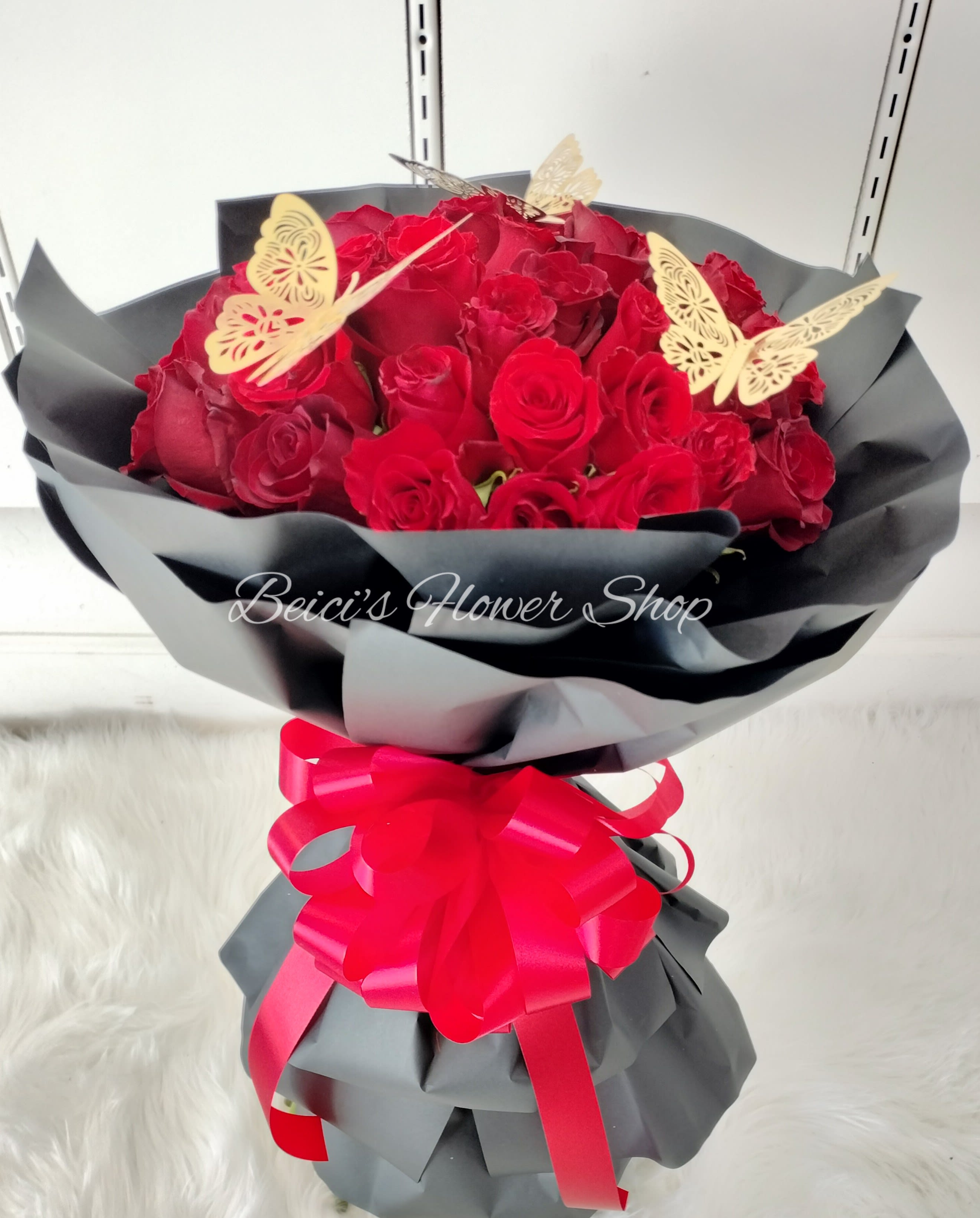 Bouquet of red roses wrapped in black paper with a pink ribbon