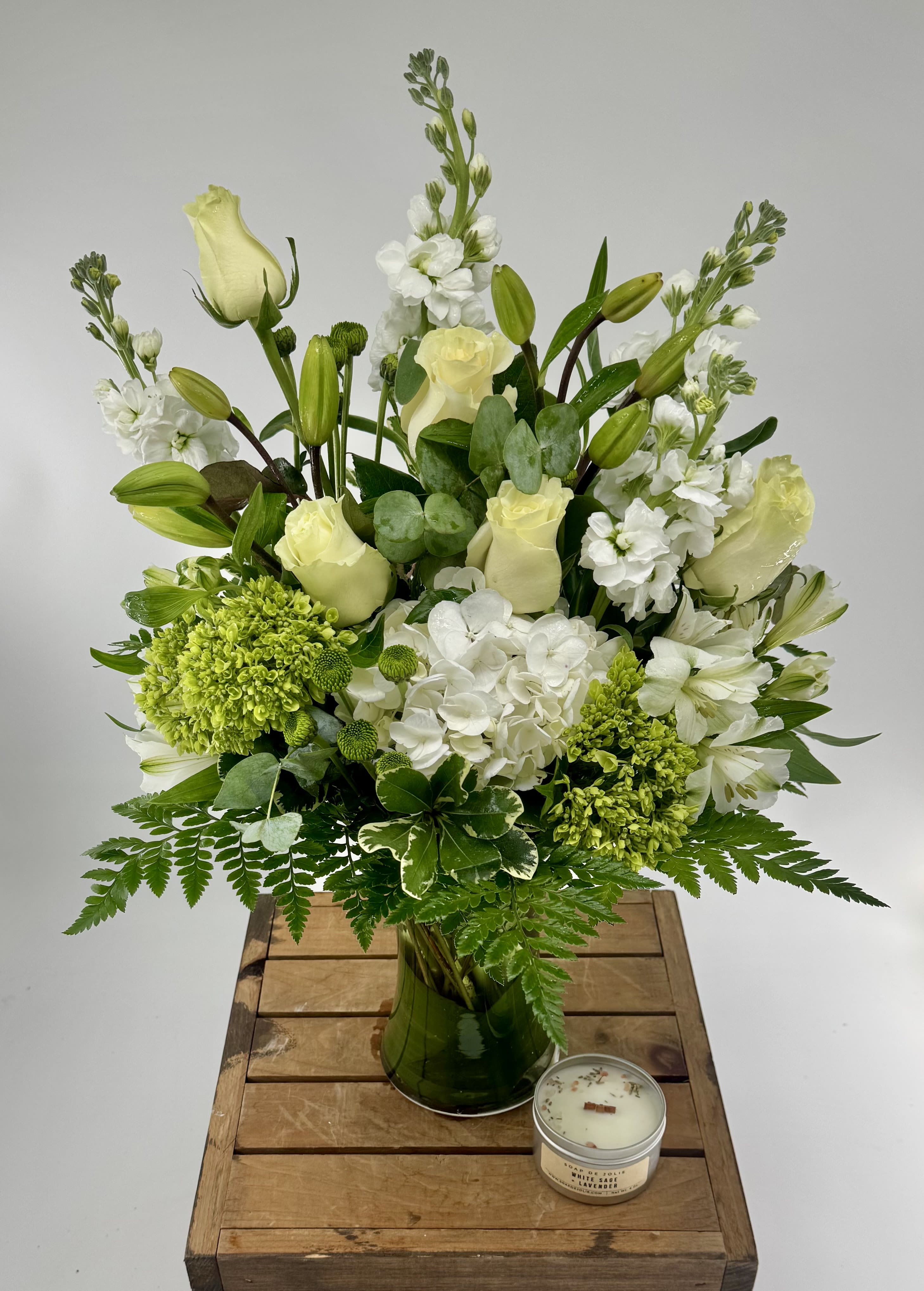 Botanic Delight (BB) - Step into a realm of pure sophistication and timeless beauty with our "Ethereal Elegance" floral arrangement, a graceful masterpiece that exudes a sense of tranquility and refined elegance. This enchanting composition features a sublime combination of pristine white roses, verdant green dianthus, delicate white lilies, majestic white snapdragons, and luxuriant premium greenery, coming together in a harmonious display of purity and poise.