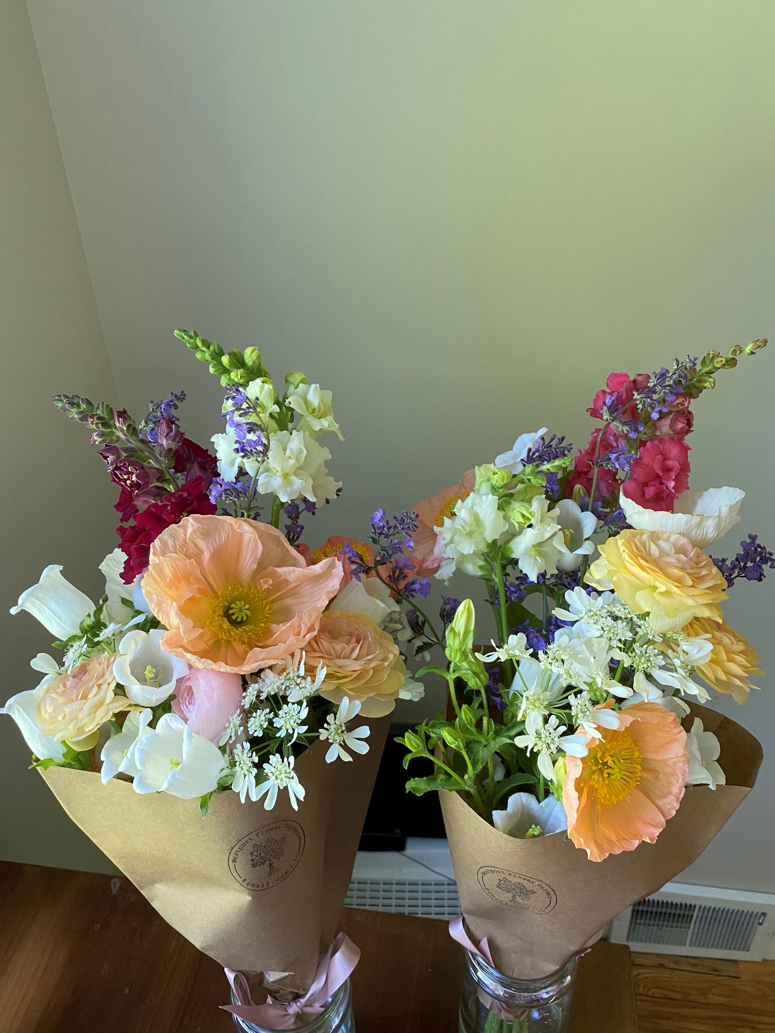 Two mixed bouquets with pastel poppies, snapdragons, and daisies in kraft wrap
